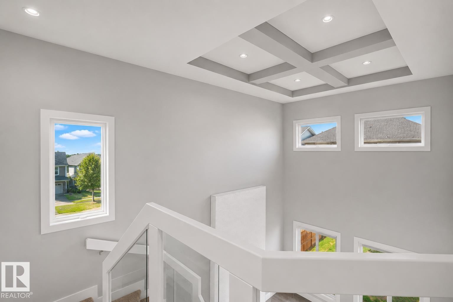Staircase with modern glass railing and white newel posts, featuring a coffered ceiling with recessed lighting. Virtually Staged. - 635 42 Street, Edmonton, AB - Indoor Photo Showing Other Room