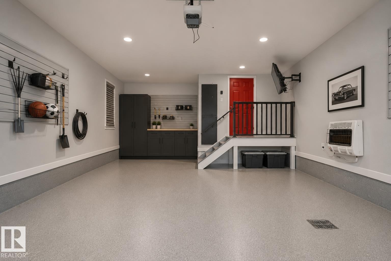 Spacious garage featuring epoxy flooring, built-in cabinetry, a utility sink, and wall-mounted storage systems. Virtually Staged. - 635 42 Street, Edmonton, AB - Indoor