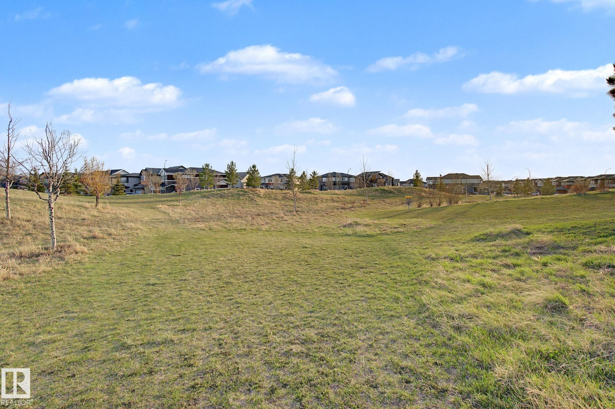Expansive grassy terrain with rolling hills and distant residential structures. Nearby Park - 635 42 Street, Edmonton, AB - Outdoor With View