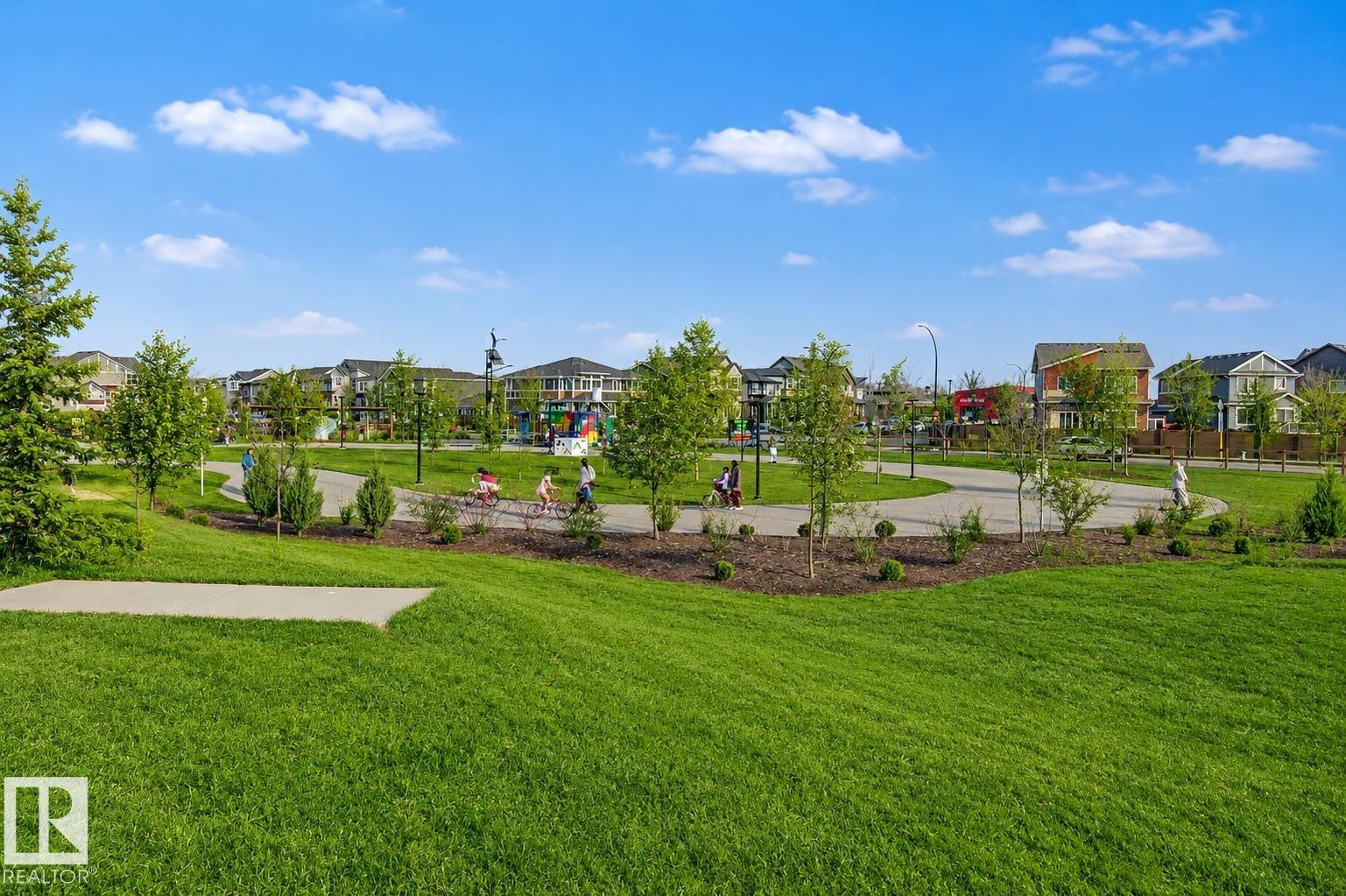 Expansive green space featuring manicured lawns, paved walking paths, and mature trees. Lawn enhanced for summer look. - 635 42 Street, Edmonton, AB - Outdoor