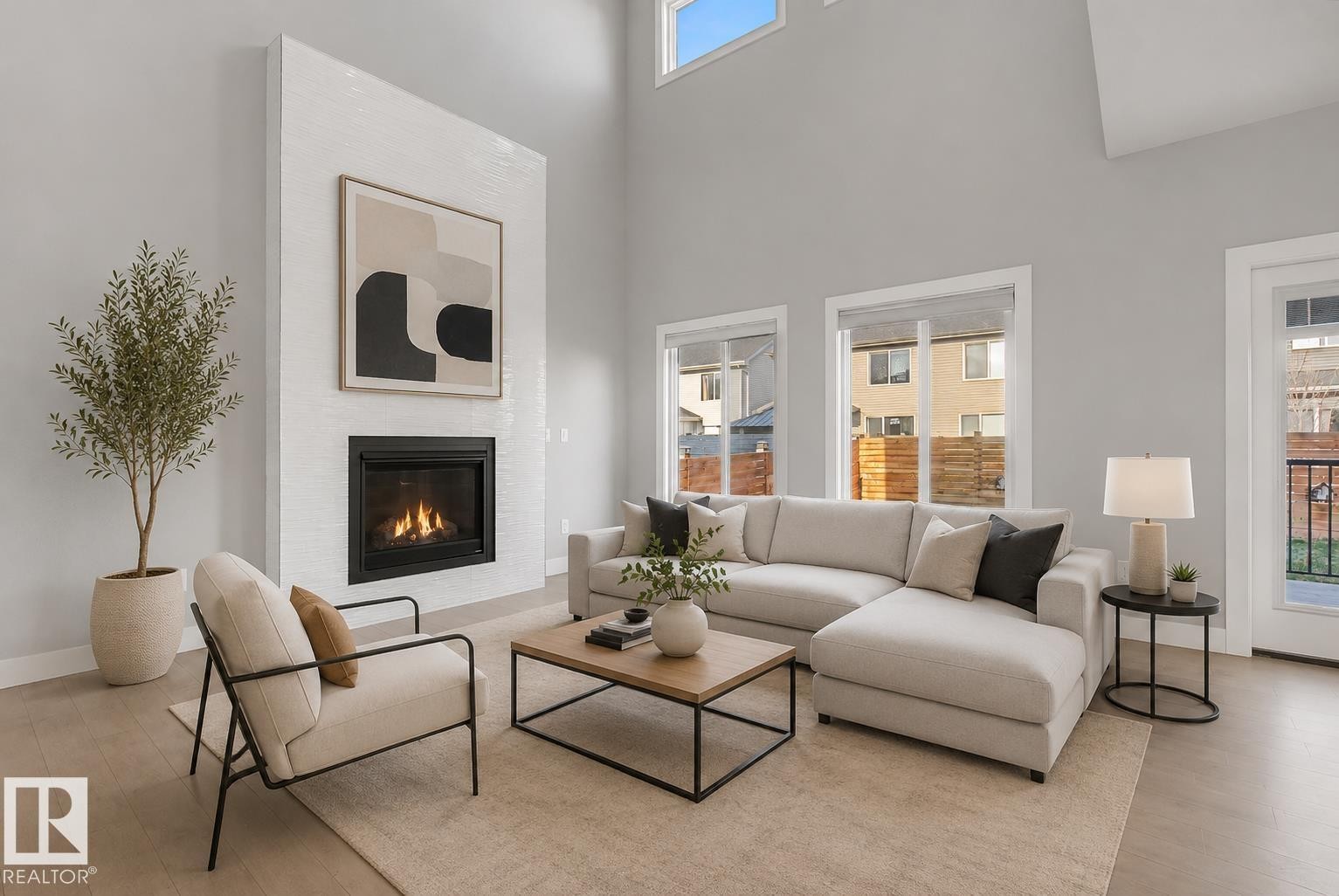 Living room featuring a tall, tiled fireplace surround, high ceilings, and light wood-finish flooring. Virtually Staged. - 635 42 Street, Edmonton, AB - Indoor Photo Showing Living Room With Fireplace