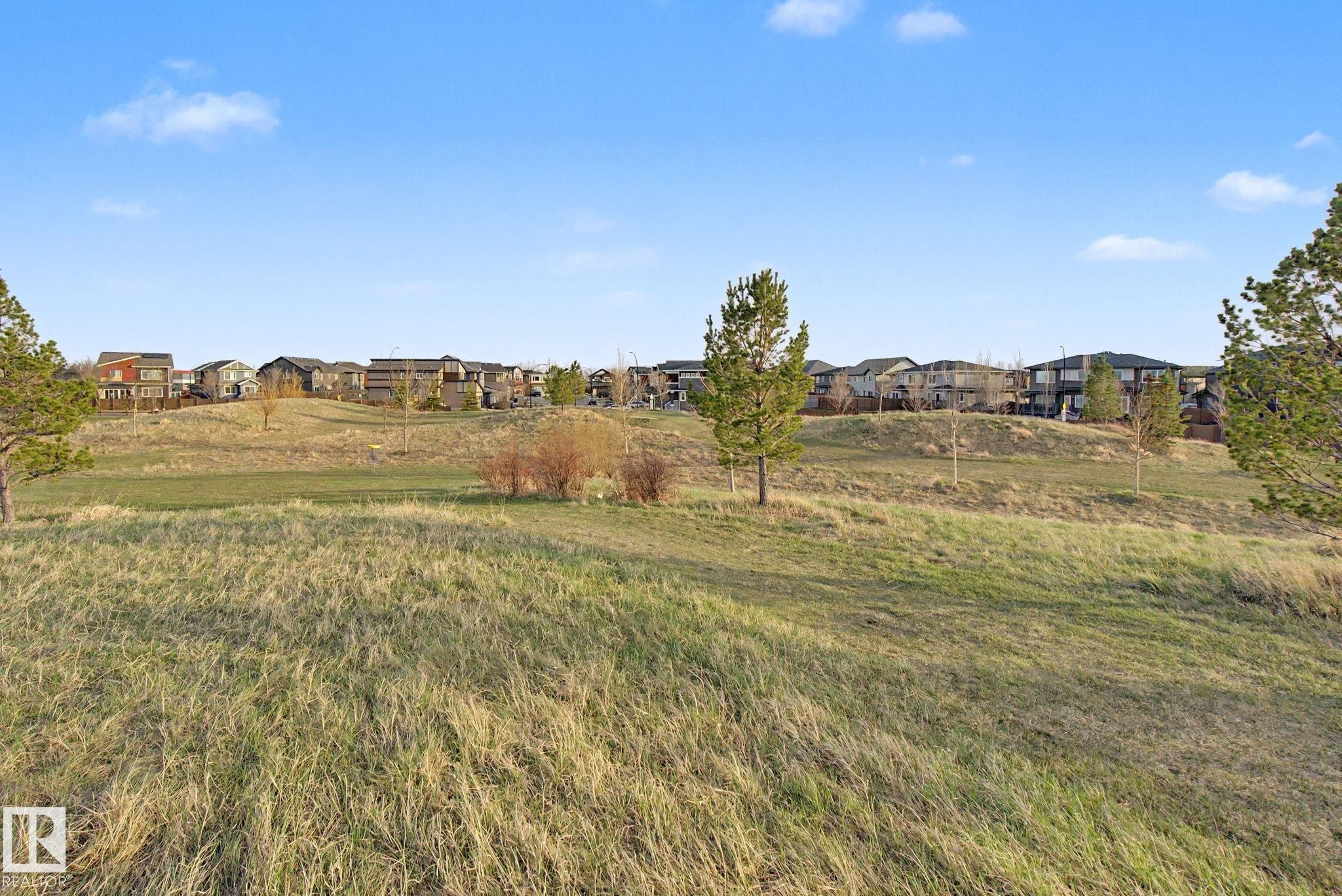 Expansive grassy landscape with scattered mature trees and distant residential properties under a clear sky - 635 42 Street, Edmonton, AB - Outdoor With View