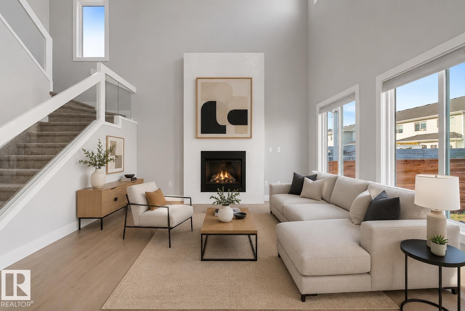 Two-story living area featuring a fireplace with a white surround, tall ceilings, and large windows. Virtually Staged. - 635 42 Street, Edmonton, AB - Indoor Photo Showing Living Room With Fireplace