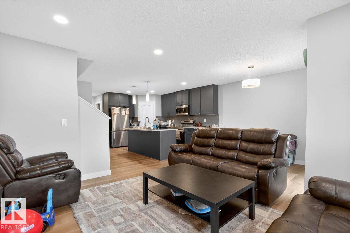 Open-concept living area featuring light wood-finish flooring, recessed lighting, and a contemporary kitchen - 3214 9 Street, Edmonton, AB - Indoor Photo Showing Living Room