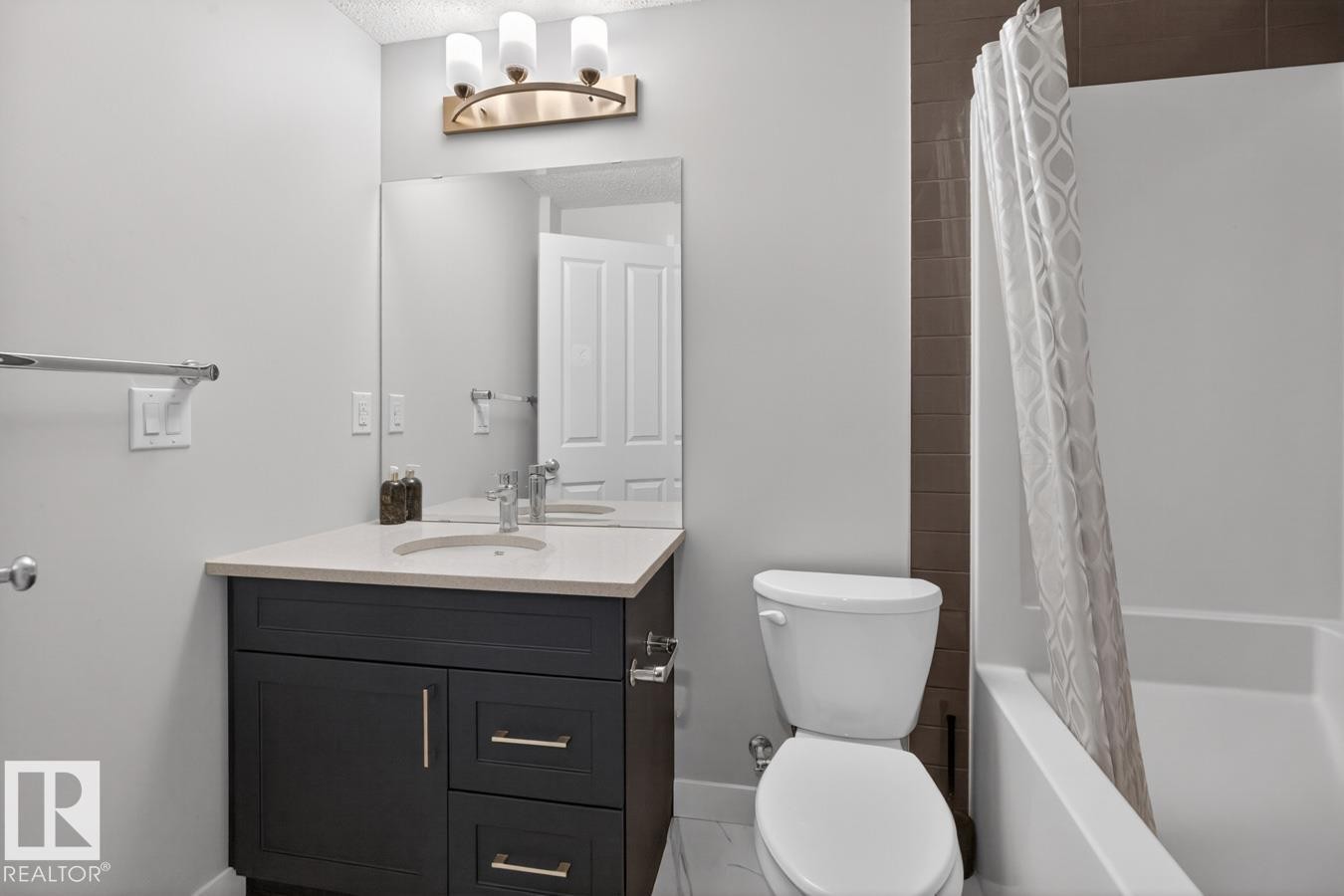 Bathroom featuring a dark wood-finish vanity with a light-toned countertop, integrated sink, and brushed nickel hardware - 3214 9 Street, Edmonton, AB - Indoor Photo Showing Bathroom