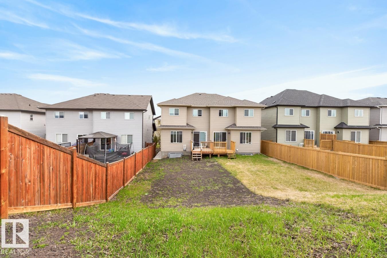 Expansive backyard featuring a partial grass lawn, partial exposed soil, and new wood fencing - 3214 9 Street, Edmonton, AB - Outdoor With Deck Patio Veranda With Backyard With Exterior
