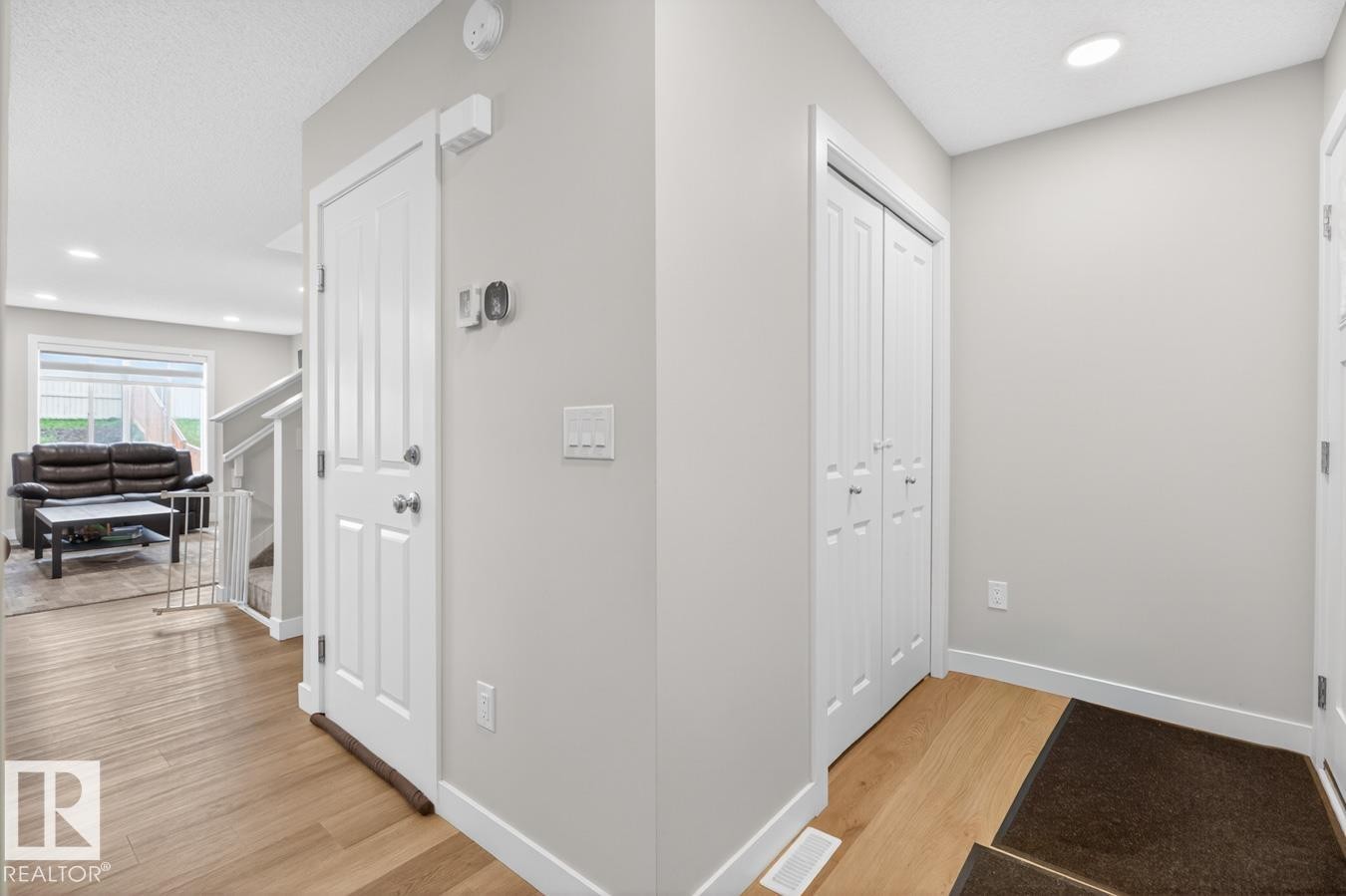Bright entryway featuring wood-finish flooring, white baseboards, a white interior door, and a bi-fold closet - 3214 9 Street, Edmonton, AB - Indoor Photo Showing Other Room