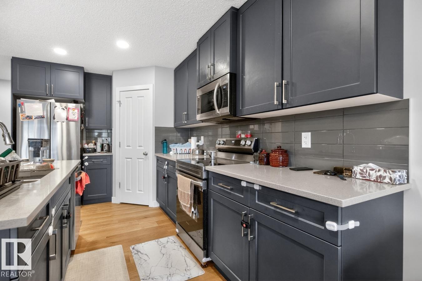 Contemporary kitchen featuring shaker-style cabinetry, light-toned countertops, a stainless steel appliance suite, and a gray subway tile backsplash - 3214 9 Street, Edmonton, AB - Indoor Photo Showing Kitchen With Stainless Steel Kitchen With Upgraded Kitchen