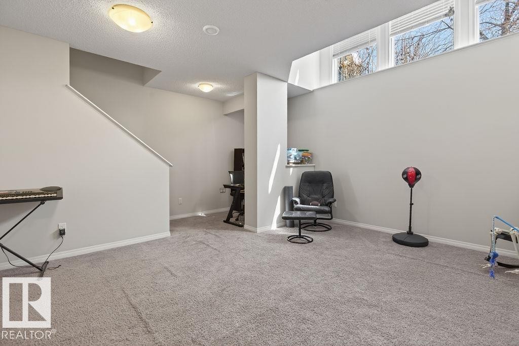 Spacious carpeted room featuring a wide staircase, recessed lighting, upper wall windows, and light gray wall paint - 17540 58 Street Nw, Edmonton, AB