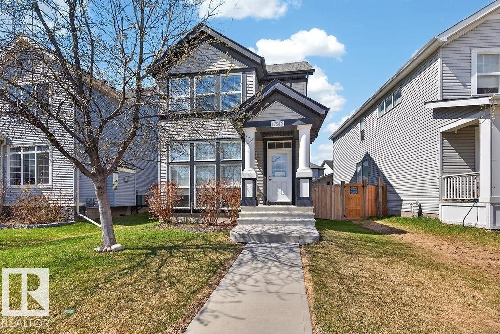 Two-story residence featuring a gray exterior with white trim, a covered entry with white columns, and multiple large windows - 17540 58 Street Nw, Edmonton, AB