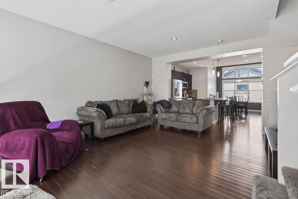 Expansive open-concept living area featuring wood-finish flooring, recessed lighting, and a neutral wall palette - 17540 58 Street Nw, Edmonton, AB