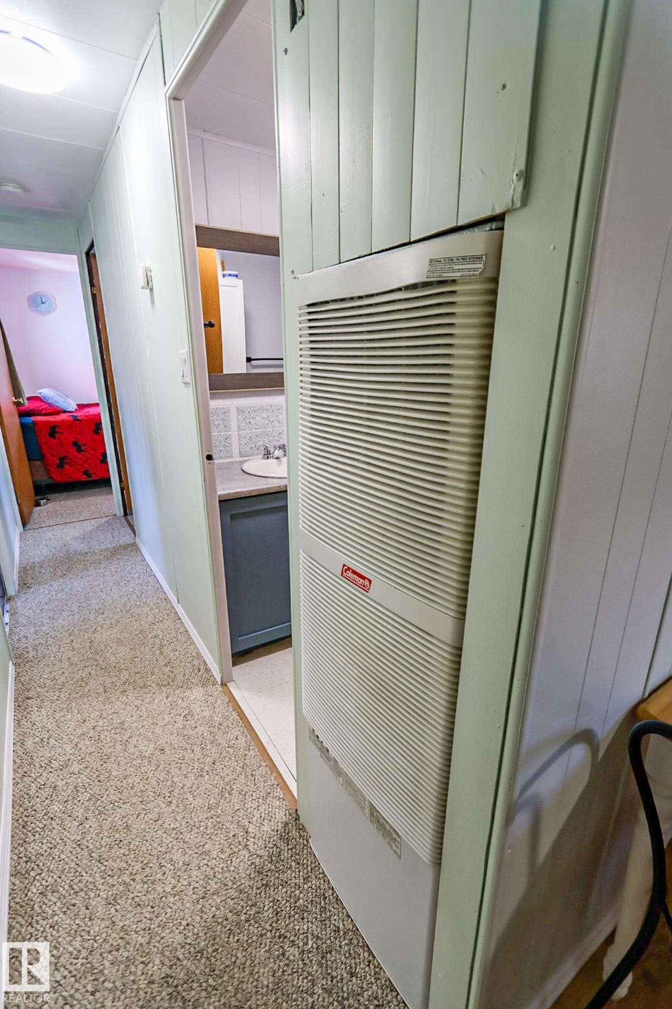 Hallway featuring textured carpet, vertical paneled walls, and a built-in heating unit - 331 60417 Range Road 124, Rural St. Paul County, AB