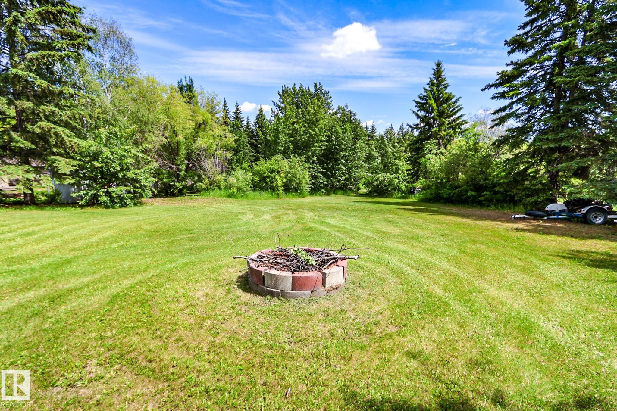 Expansive lawn area featuring a block-bordered fire pit - 331 60417 Range Road 124, Rural St. Paul County, AB