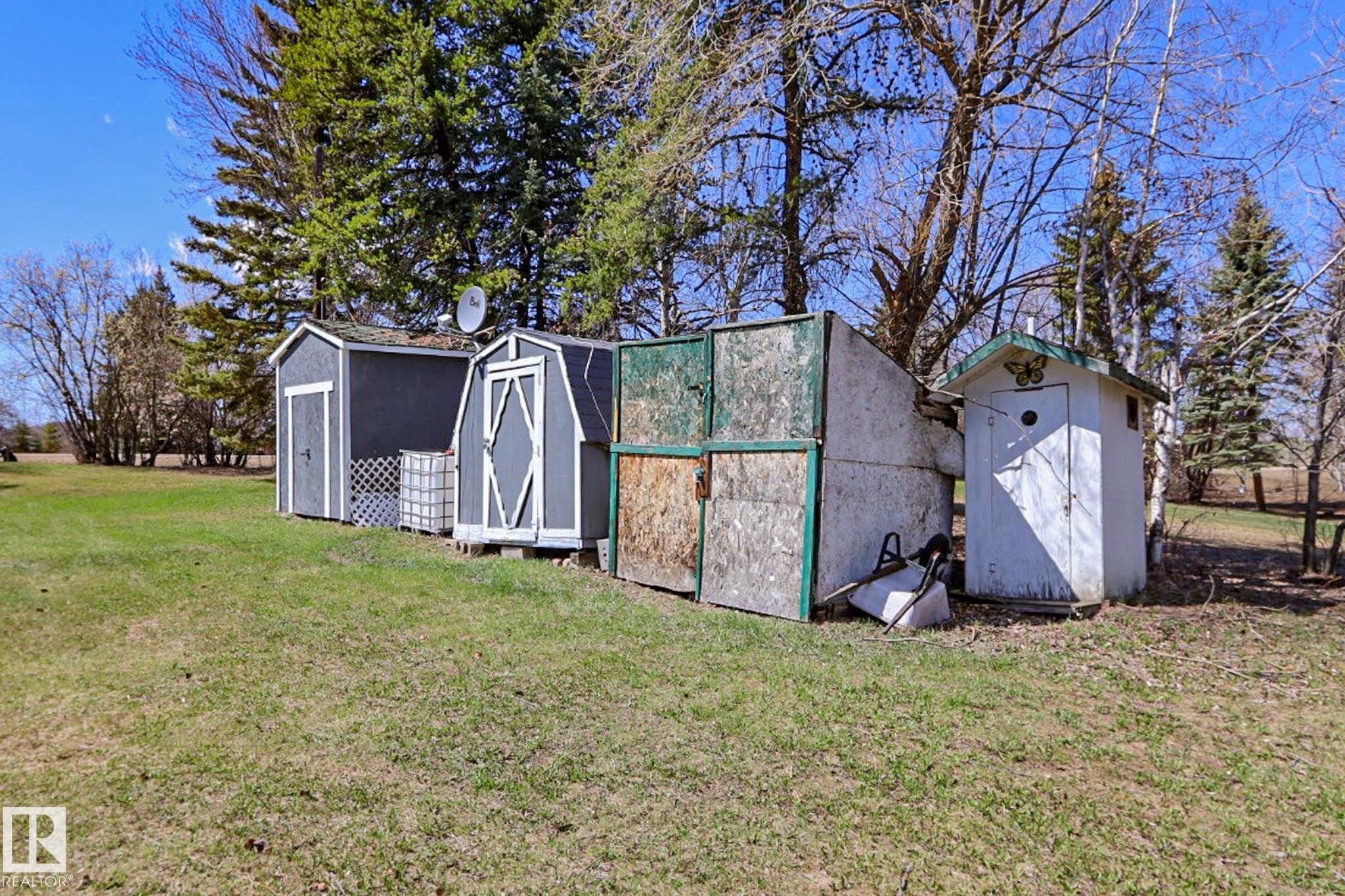 Two storage sheds with dark grey siding and white trim, alongside a smaller white utility building with a green roof accent - 331 60417 Range Road 124, Rural St. Paul County, AB