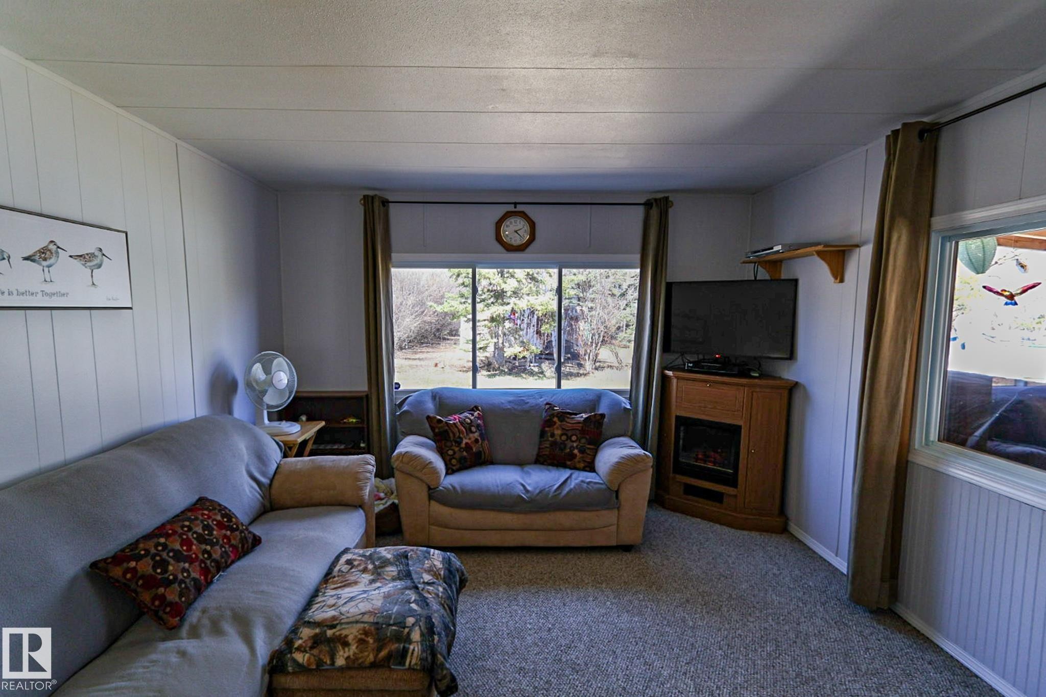 Living area featuring a large picture window, light gray carpeting, and paneled walls - 331 60417 Range Road 124, Rural St. Paul County, AB