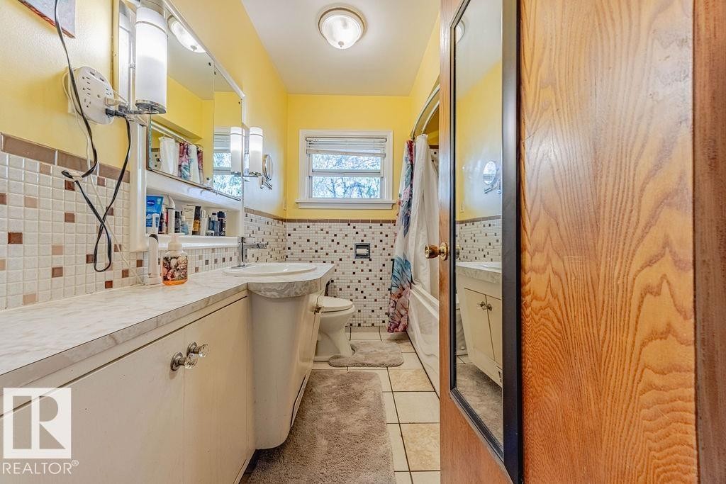 Bathroom featuring a built-in vanity with integrated sink, a window, and tile flooring - 12339 89 Street, Edmonton, AB - Indoor Photo Showing Bathroom