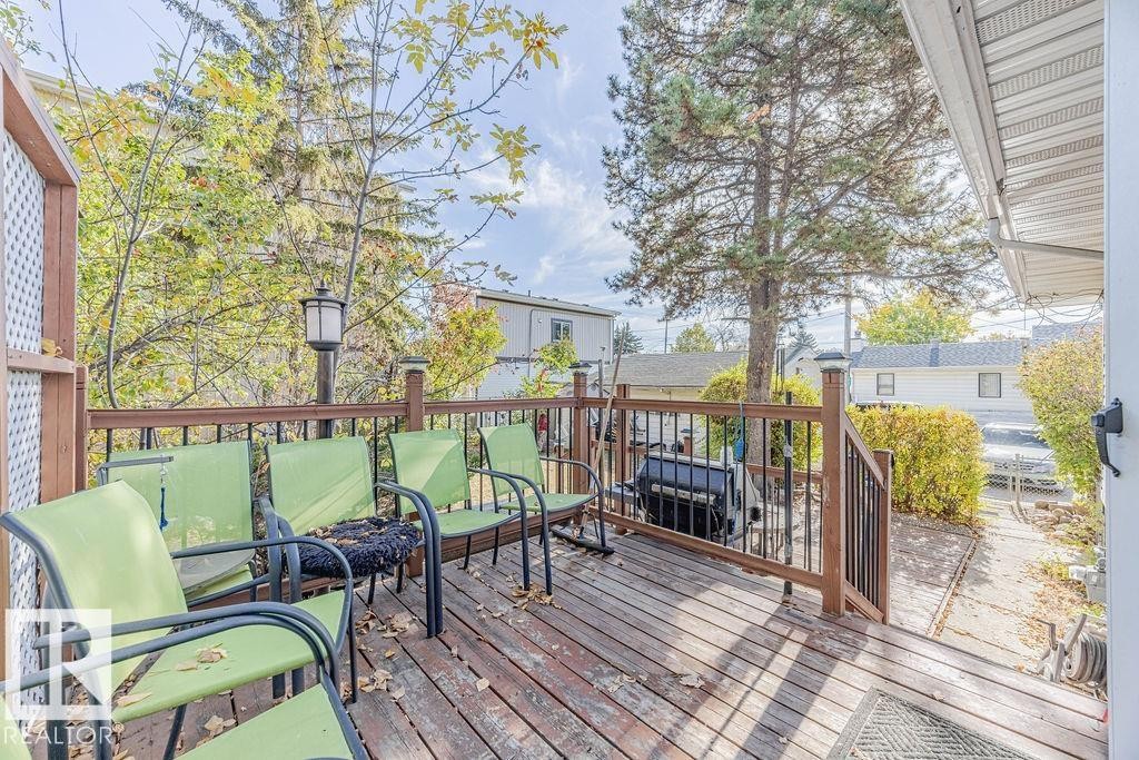 Spacious outdoor deck featuring wood-finish flooring, dark wood railings with black metal balusters, and a built-in lattice privacy screen - 12339 89 Street, Edmonton, AB - Outdoor With Deck Patio Veranda With Exterior