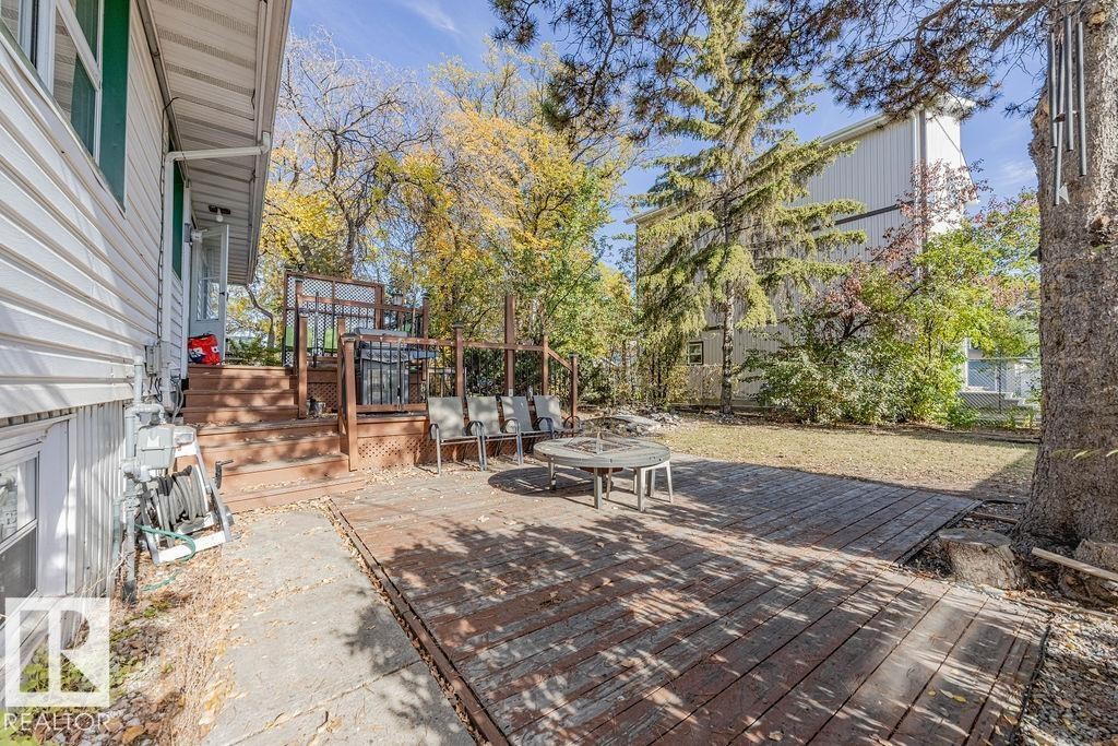 Private backyard featuring a wooden deck, a ground-level wooden patio, and a grassy lawn framed by mature trees - 12339 89 Street, Edmonton, AB - Outdoor