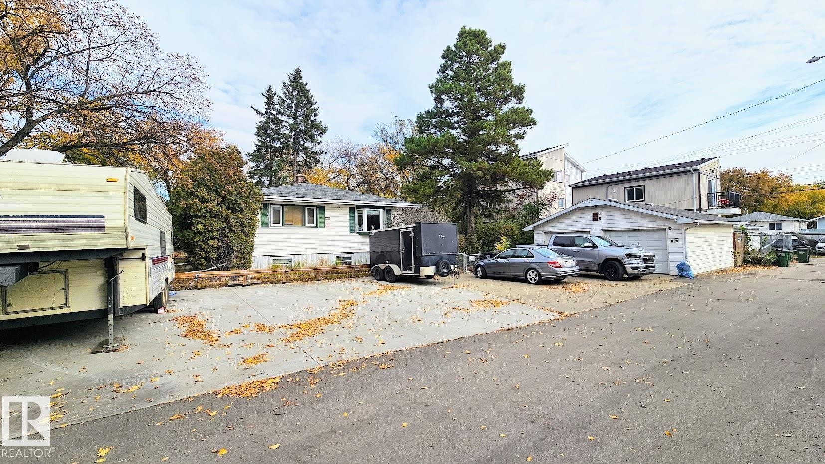 White exterior siding with green window shutters, a detached garage, and an asphalt driveway - 12339 89 Street, Edmonton, AB - Outdoor