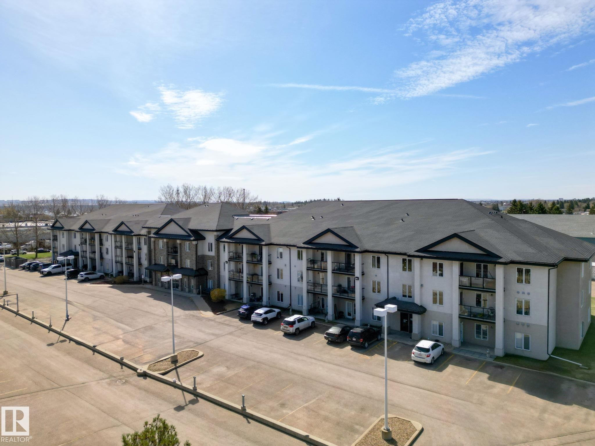 Multi-story apartment building with a dark shingle roof and light-colored siding - 220 80A Kelloway Crescent, Red Deer, AB - Outdoor
