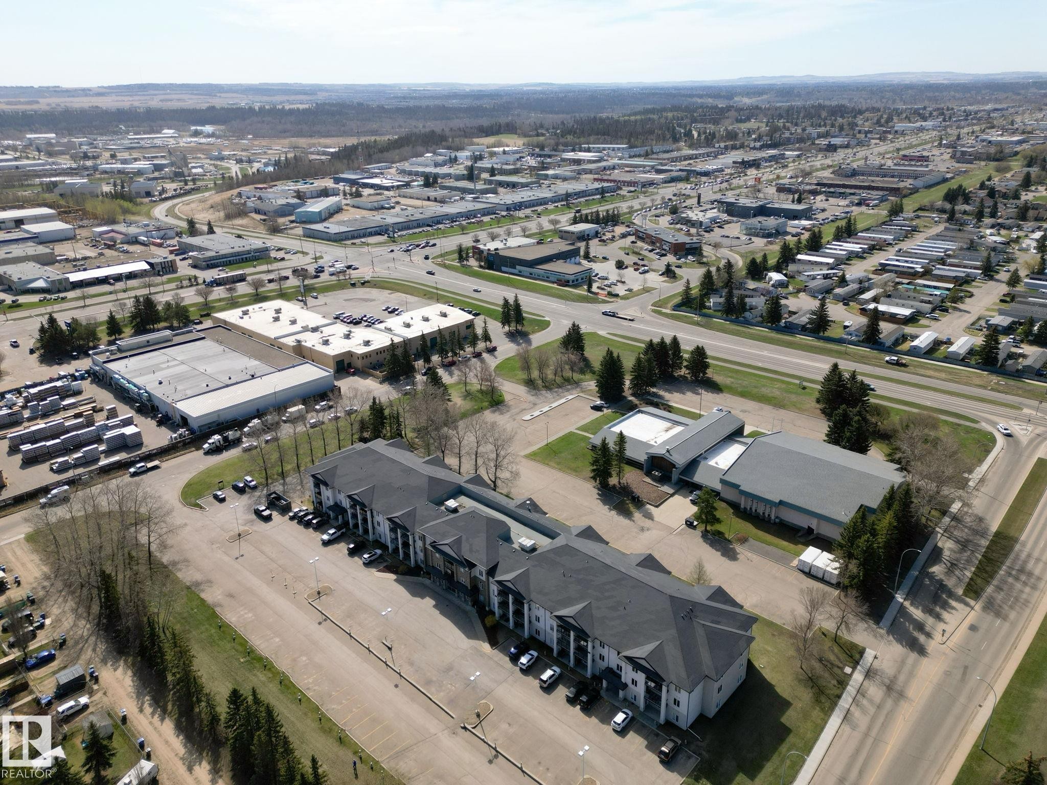 Aerial perspective showcasing a multi-building property with extensive paved parking areas - 220 80A Kelloway Crescent, Red Deer, AB - Outdoor With View