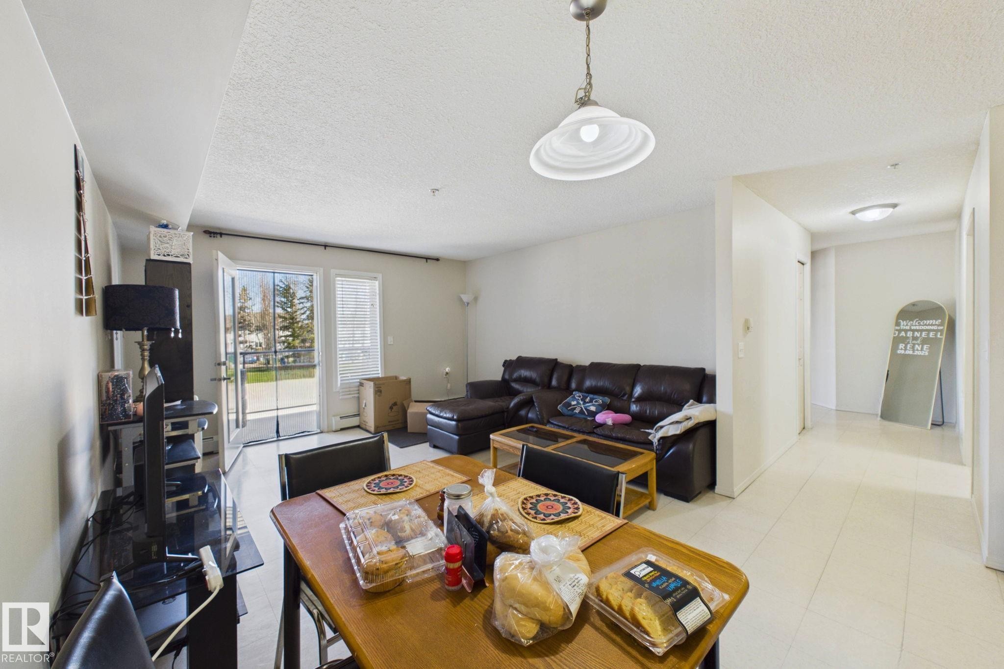 Open concept living area with white walls and light-colored tile flooring - 220 80A Kelloway Crescent, Red Deer, AB - Indoor Photo Showing Living Room
