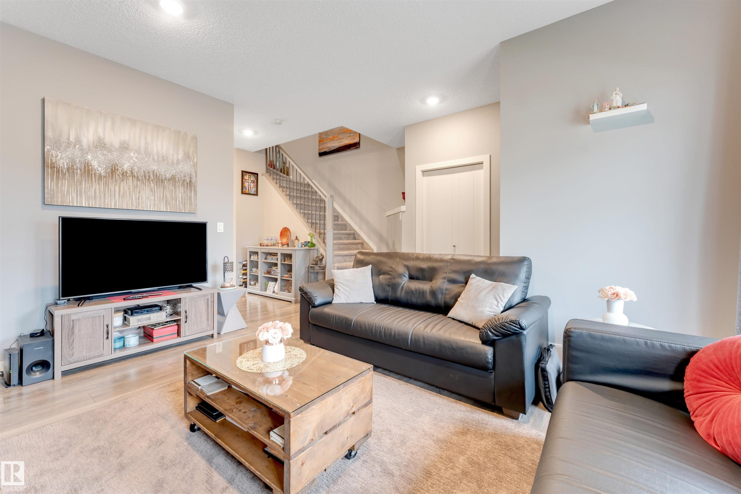 Bright living space featuring recessed lighting, light wood-finish flooring, and a staircase with white risers and handrails - 2652 Maple Way, Edmonton, AB - Indoor Photo Showing Living Room
