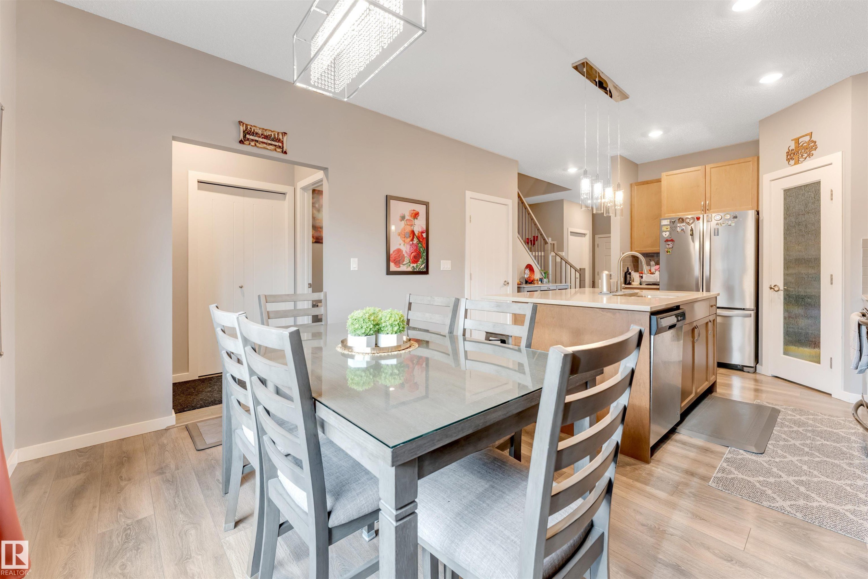Open-concept dining area featuring wood-finish flooring, a contemporary linear chandelier, and neutral wall tones - 2652 Maple Way, Edmonton, AB - Indoor Photo Showing Dining Room