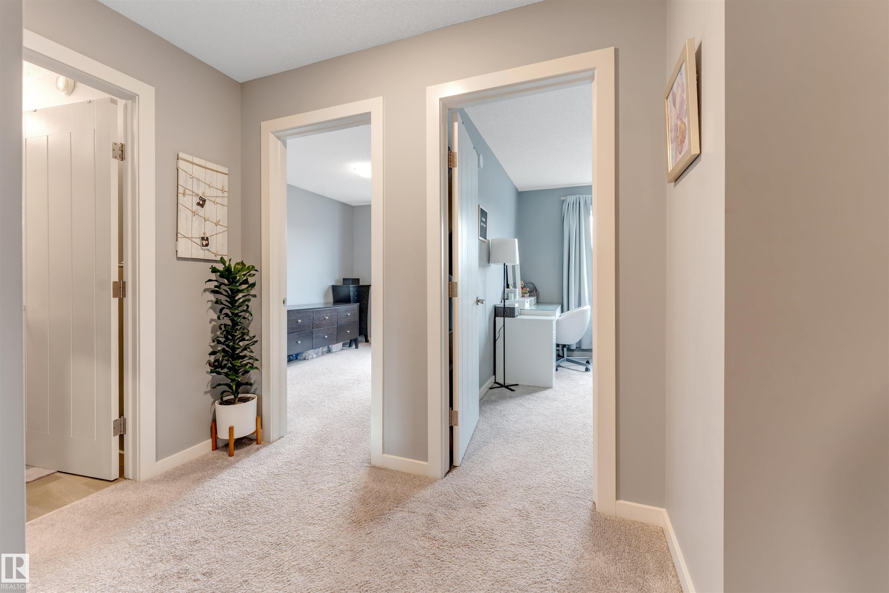 Carpeted hallway with light gray walls, white trim, and multiple doorways leading to other rooms - 2652 Maple Way, Edmonton, AB - Indoor Photo Showing Other Room