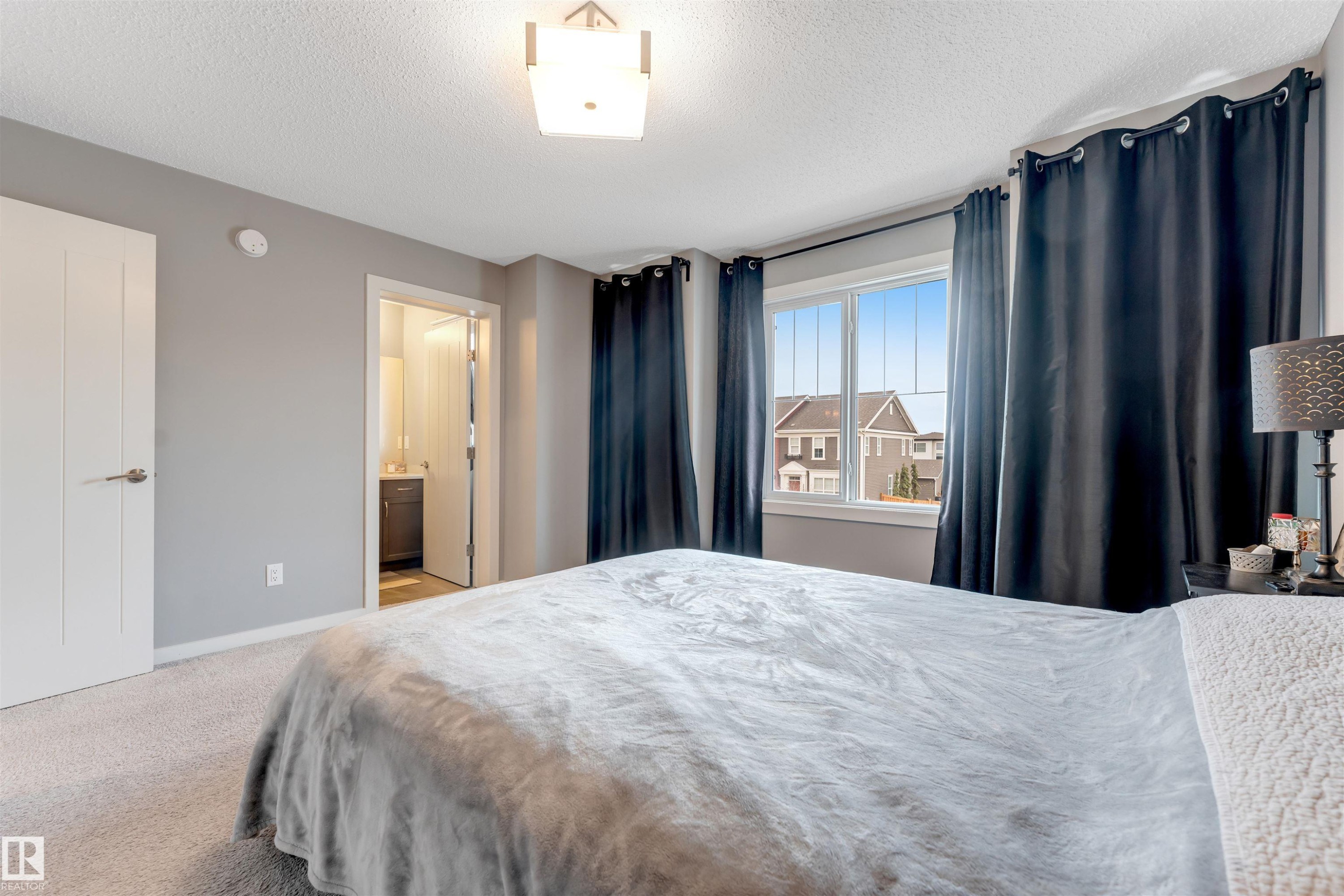 Spacious room featuring light gray walls, plush carpeting, a large window, and a ceiling-mounted light fixture - 2652 Maple Way, Edmonton, AB - Indoor Photo Showing Bedroom