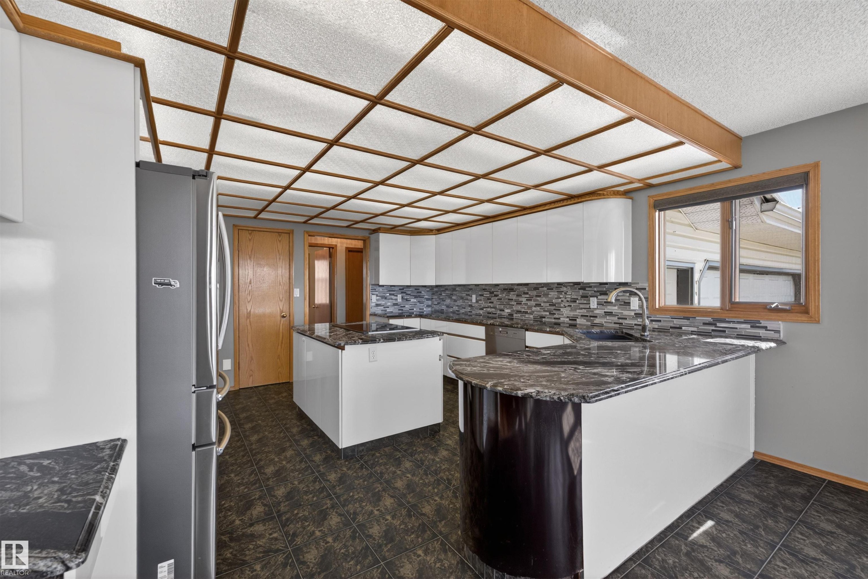 Kitchen featuring dark granite countertops, a built-in stainless steel refrigerator, white cabinetry, and a mosaic tile backsplash - 19403 Fort Road, Edmonton, AB - Indoor