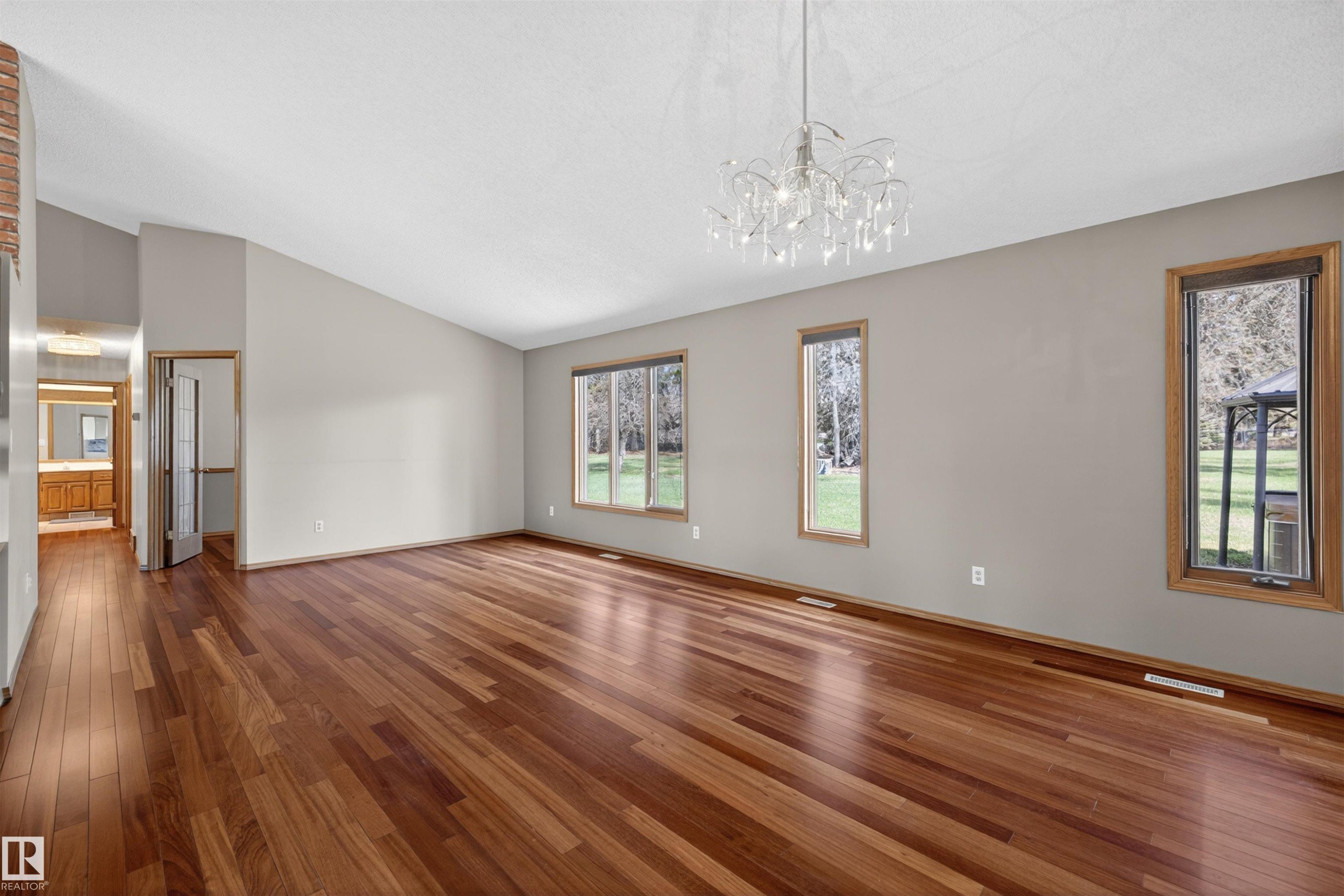 Spacious room featuring wood-finish flooring, vaulted ceilings, and a decorative chandelier - 19403 Fort Road, Edmonton, AB - Indoor Photo Showing Other Room
