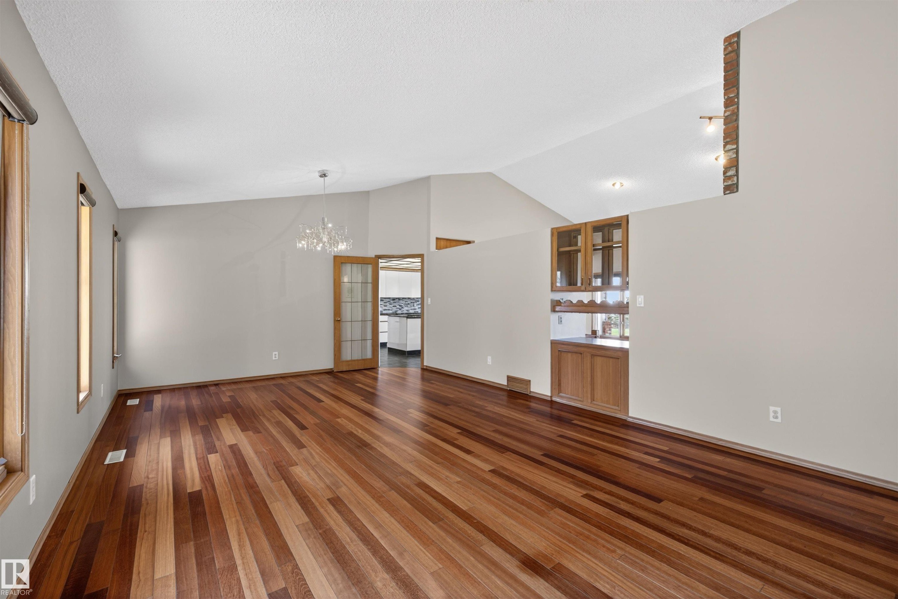 Spacious room featuring rich wood-finish flooring, soaring vaulted ceilings, and multiple windows with wood trim - 19403 Fort Road, Edmonton, AB - Indoor Photo Showing Other Room