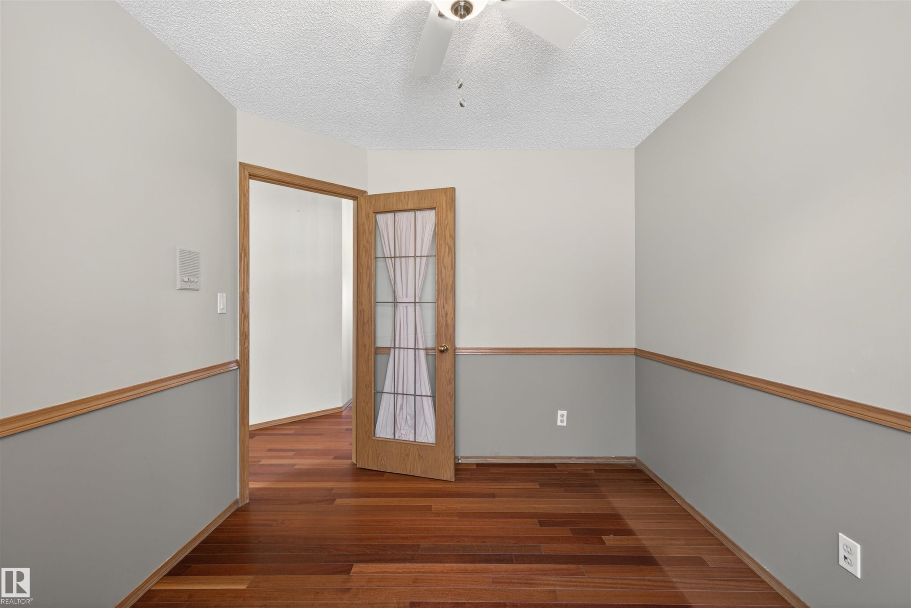 Room featuring wood-finish flooring and two-tone wall paint with wood trim - 19403 Fort Road, Edmonton, AB - Indoor Photo Showing Other Room