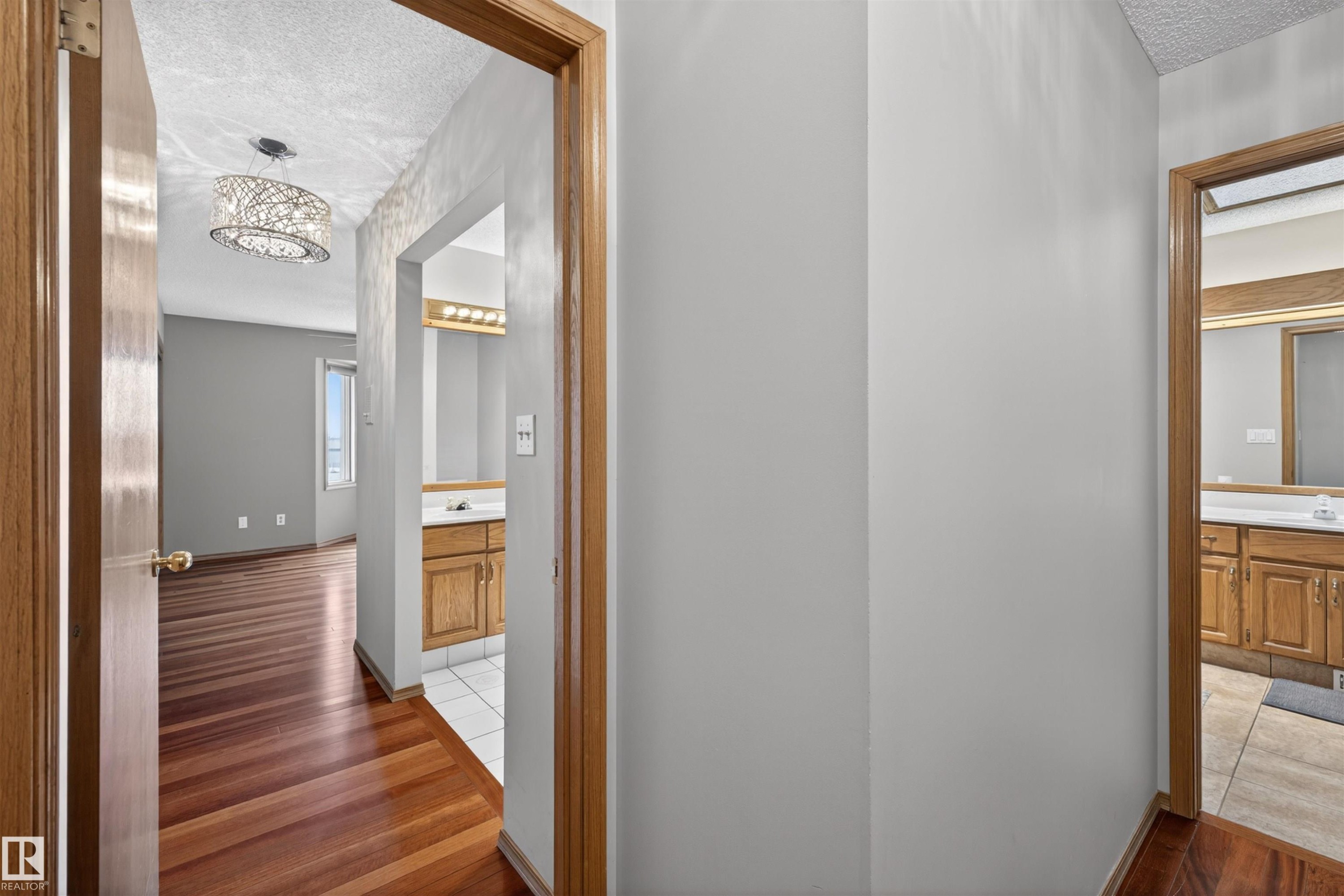 Hallway featuring wood-finish flooring, light gray wall paint, and natural wood trim - 19403 Fort Road, Edmonton, AB - Indoor