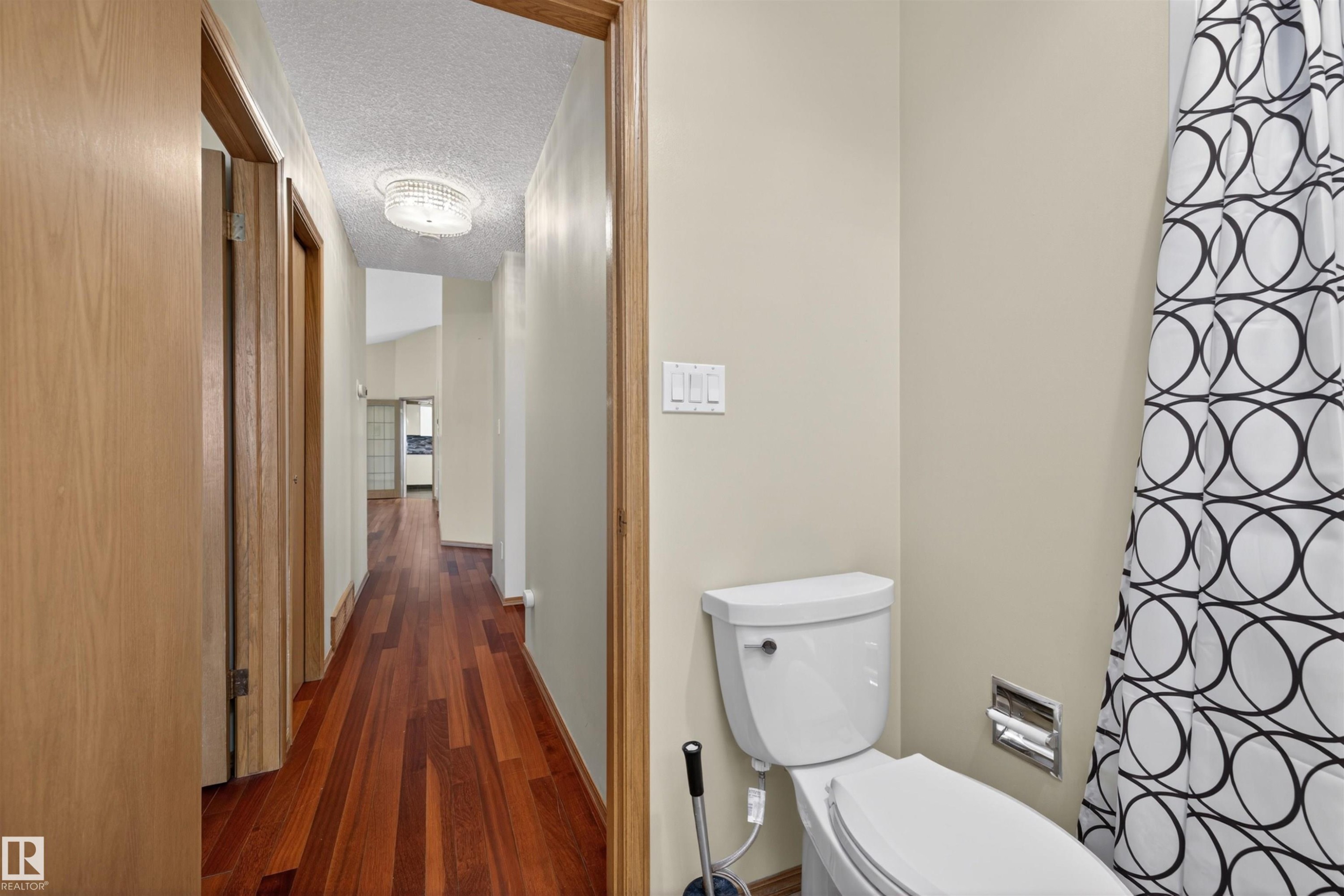 Hardwood-style flooring extends through the hallway, complemented by light-toned wall paint - 19403 Fort Road, Edmonton, AB - Indoor Photo Showing Bathroom
