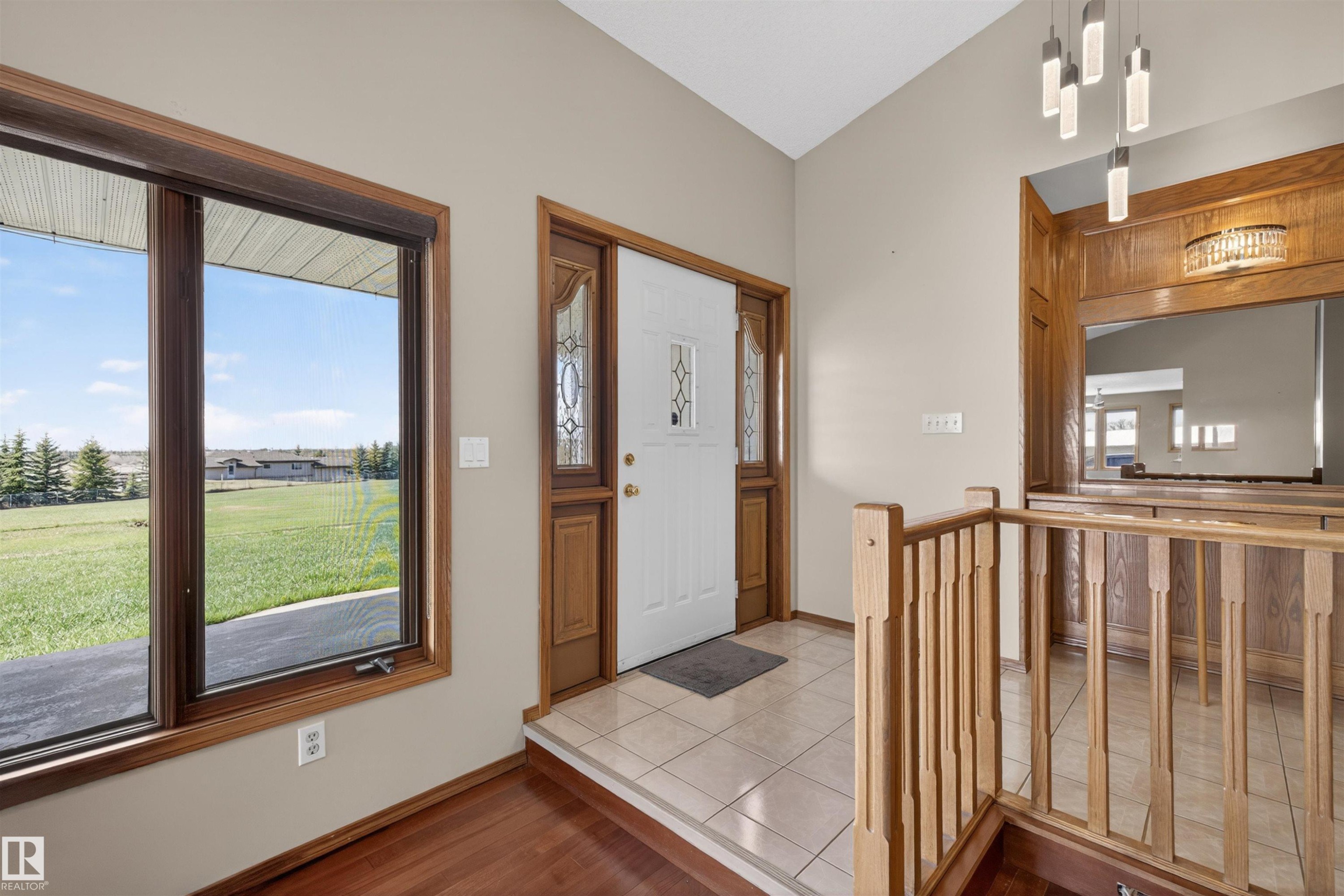 Entryway with wood-finish flooring, a white front door with decorative glass inserts, and an expansive window with dark wood framing - 19403 Fort Road, Edmonton, AB - Indoor Photo Showing Other Room