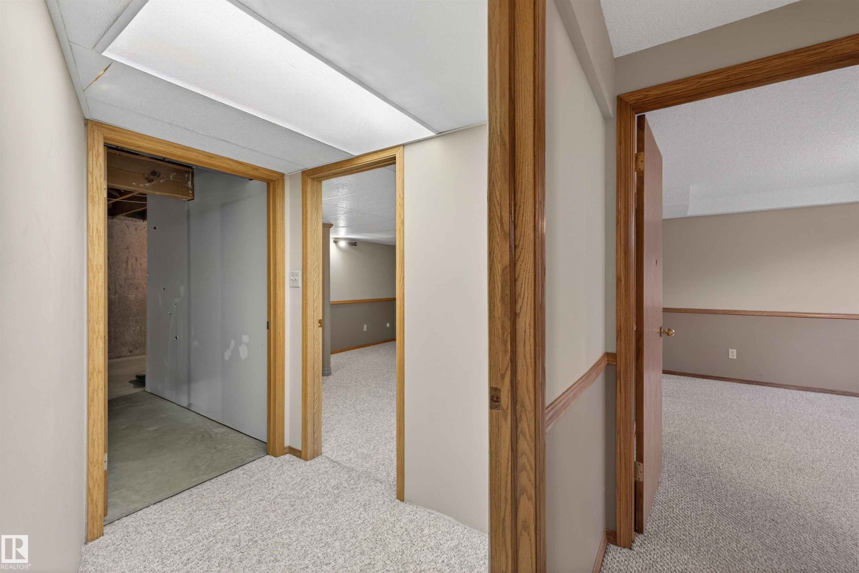 Hallway featuring light-colored carpet flooring, wood door casings, and a textured drop ceiling with flush lighting - 19403 Fort Road, Edmonton, AB - Indoor