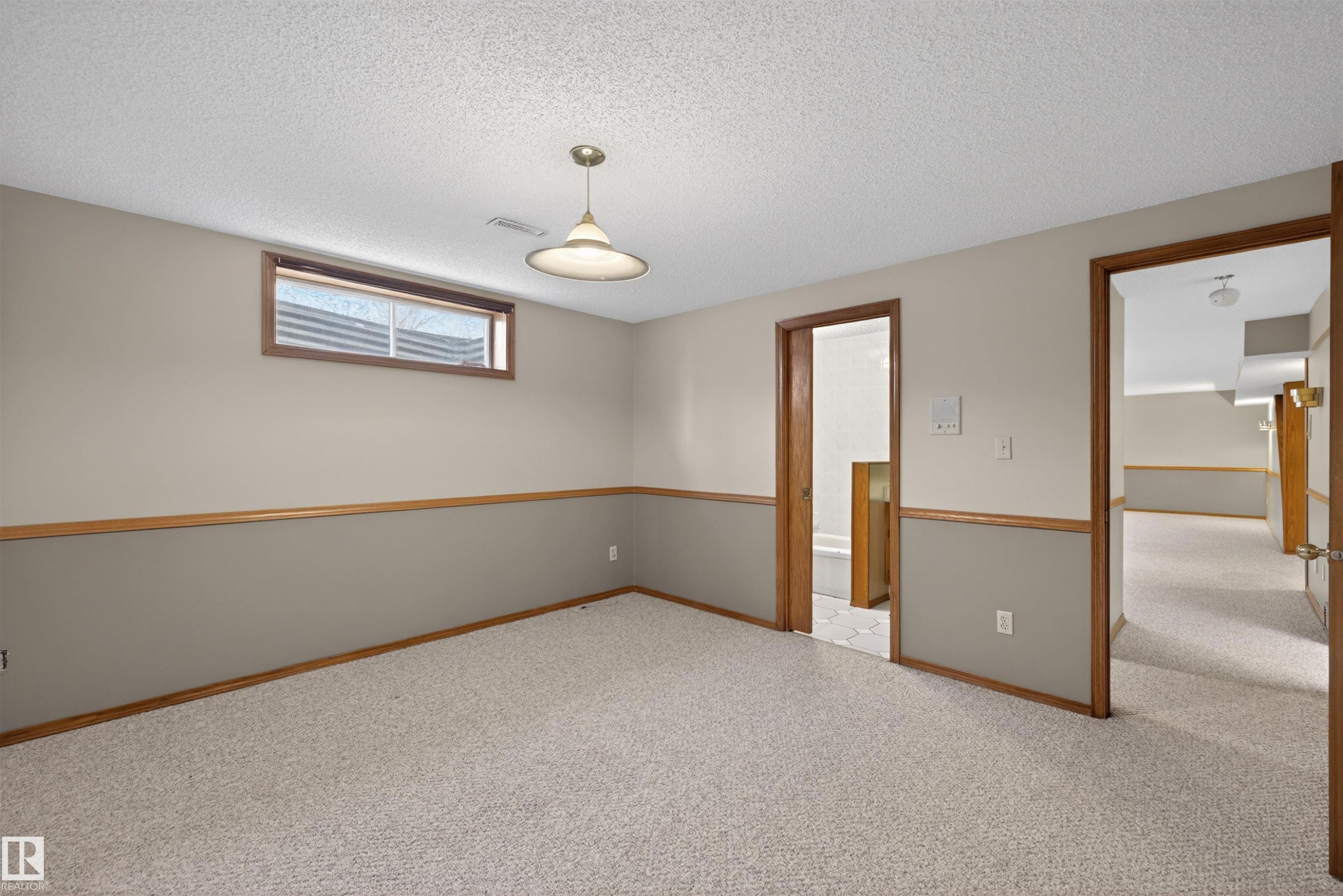 Carpeted room with a drop ceiling, wood-trimmed paneling, and a single-pane window - 19403 Fort Road, Edmonton, AB - Indoor Photo Showing Other Room