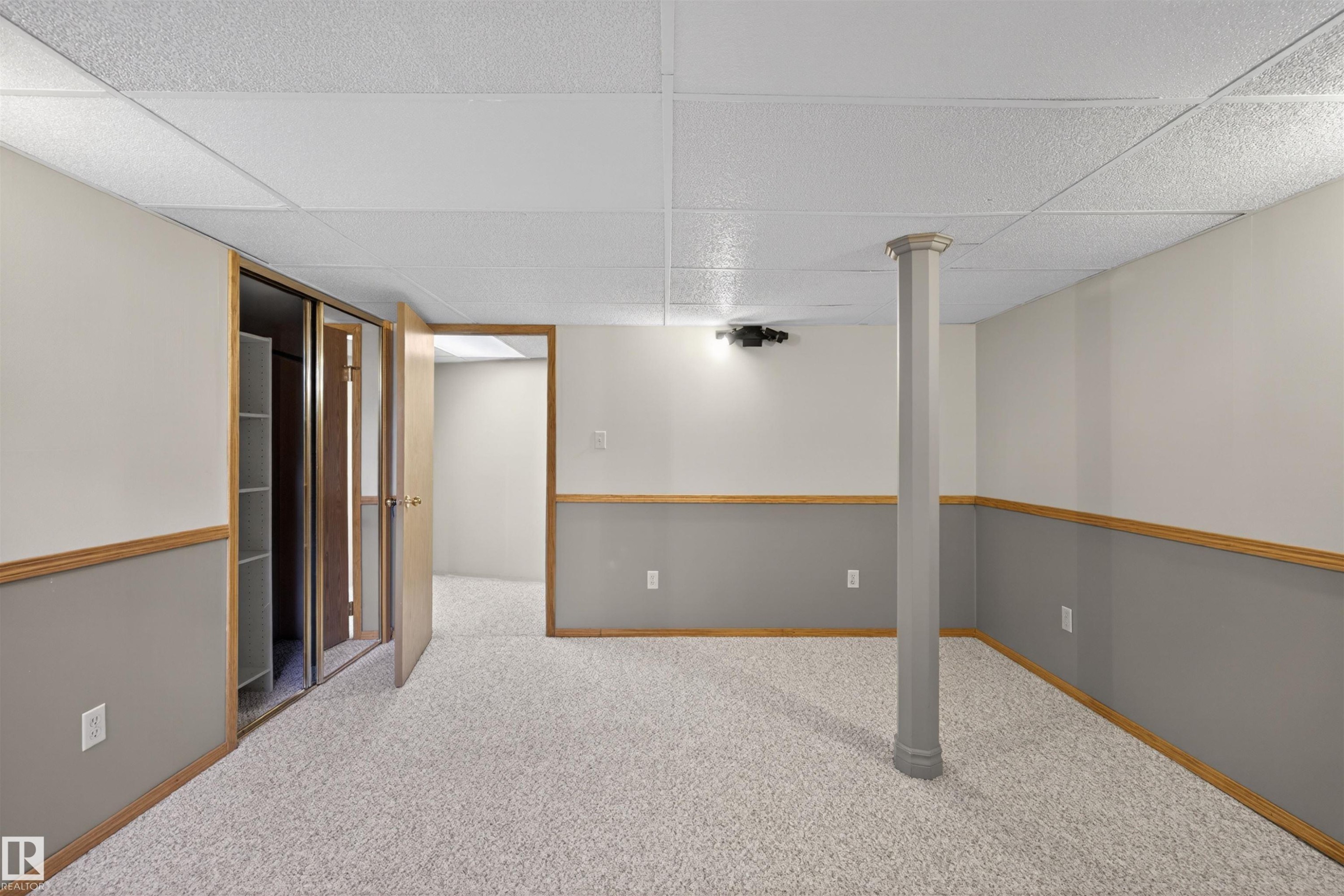 Spacious room featuring light-colored carpet flooring, two-tone painted walls with wood trim, and a drop ceiling - 19403 Fort Road, Edmonton, AB - Indoor Photo Showing Other Room