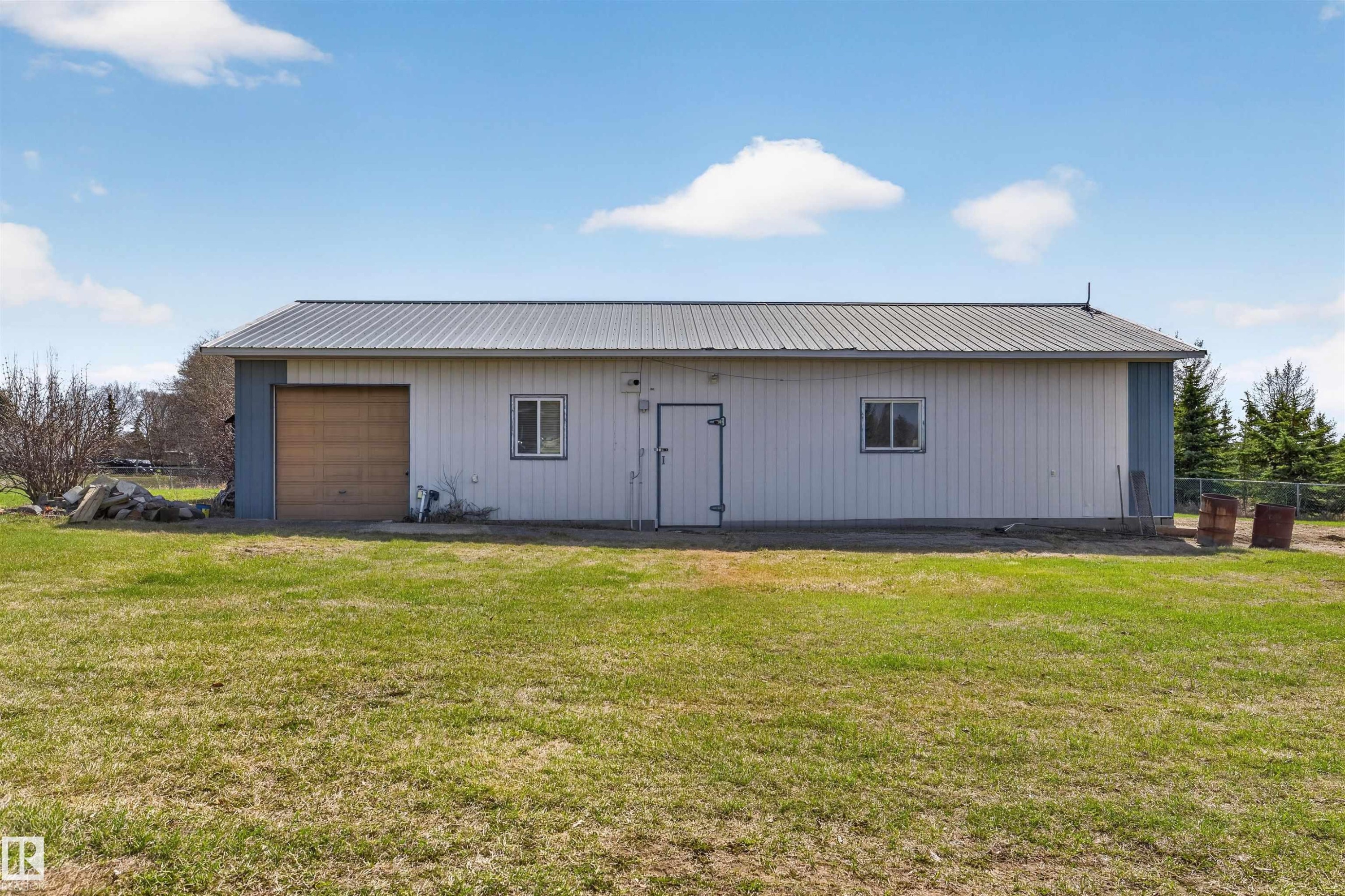 Detached outbuilding with a metal roof, light-colored siding, and a roll-up garage door - 19403 Fort Road, Edmonton, AB - Outdoor