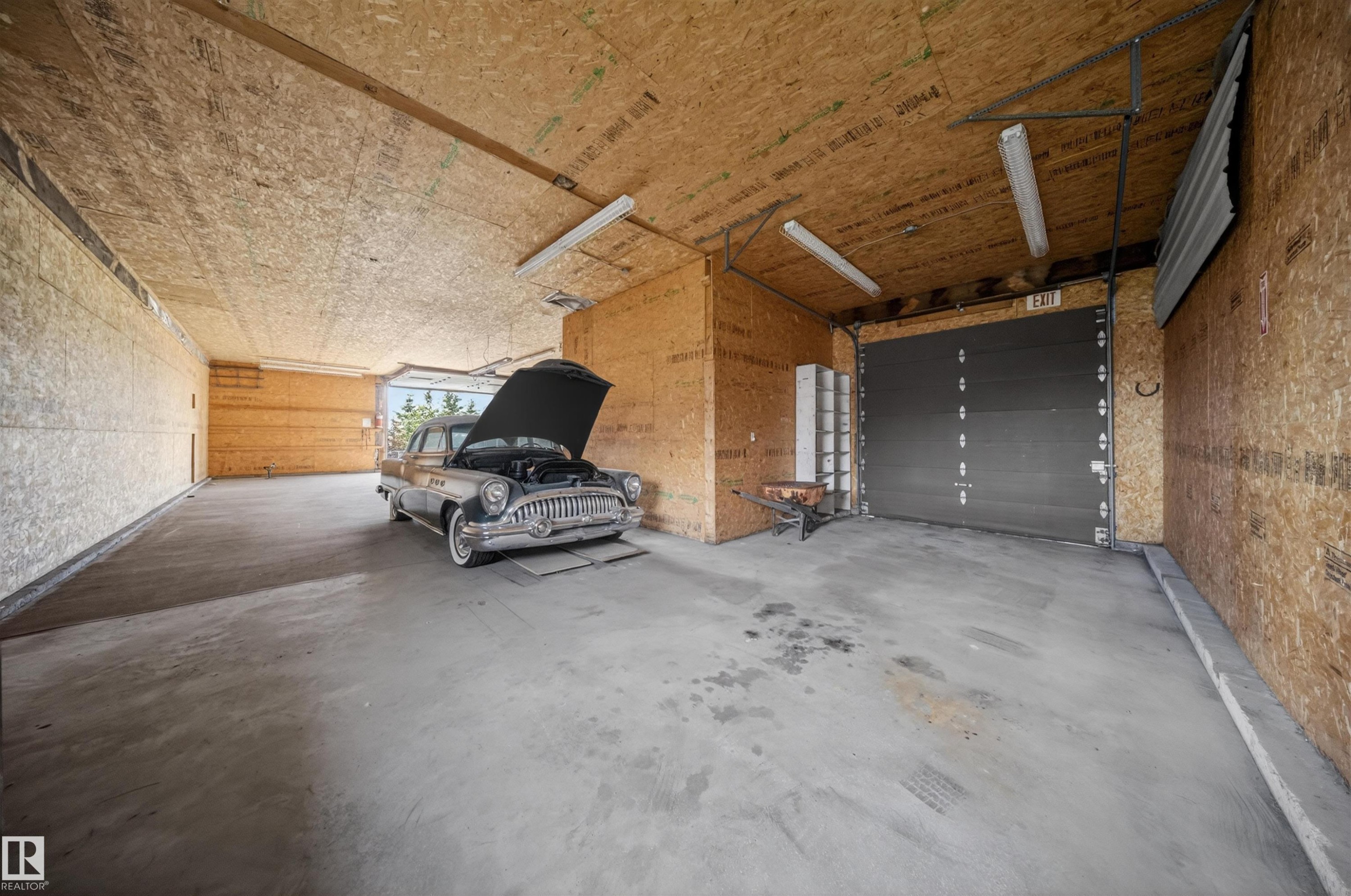 Spacious garage featuring concrete flooring, unpainted OSB walls and ceiling, and ample overhead fluorescent lighting - 19403 Fort Road, Edmonton, AB - Indoor Photo Showing Garage