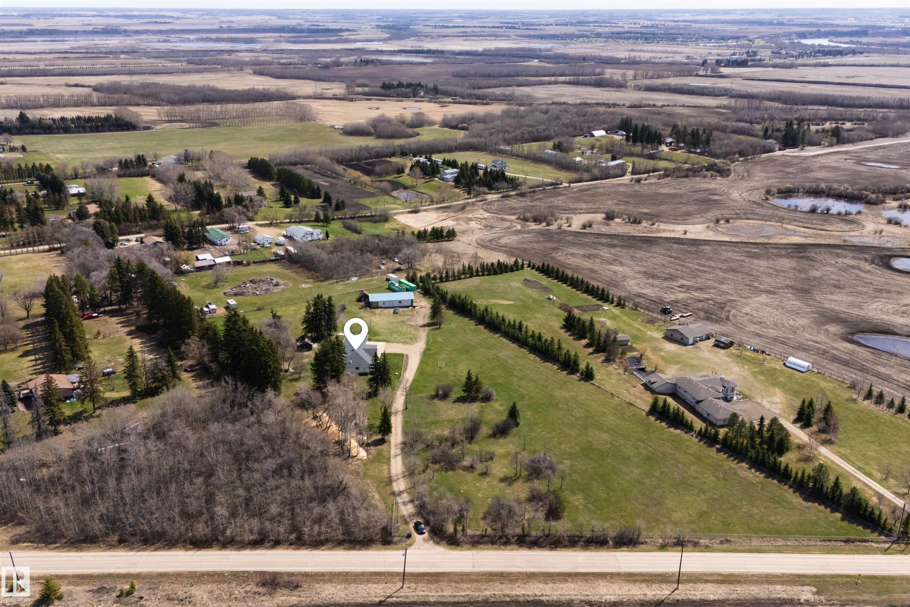 Expansive rural property featuring a main residence with a light-colored roof, surrounded by mature trees and open green spaces - 19403 Fort Road, Edmonton, AB - Outdoor With View