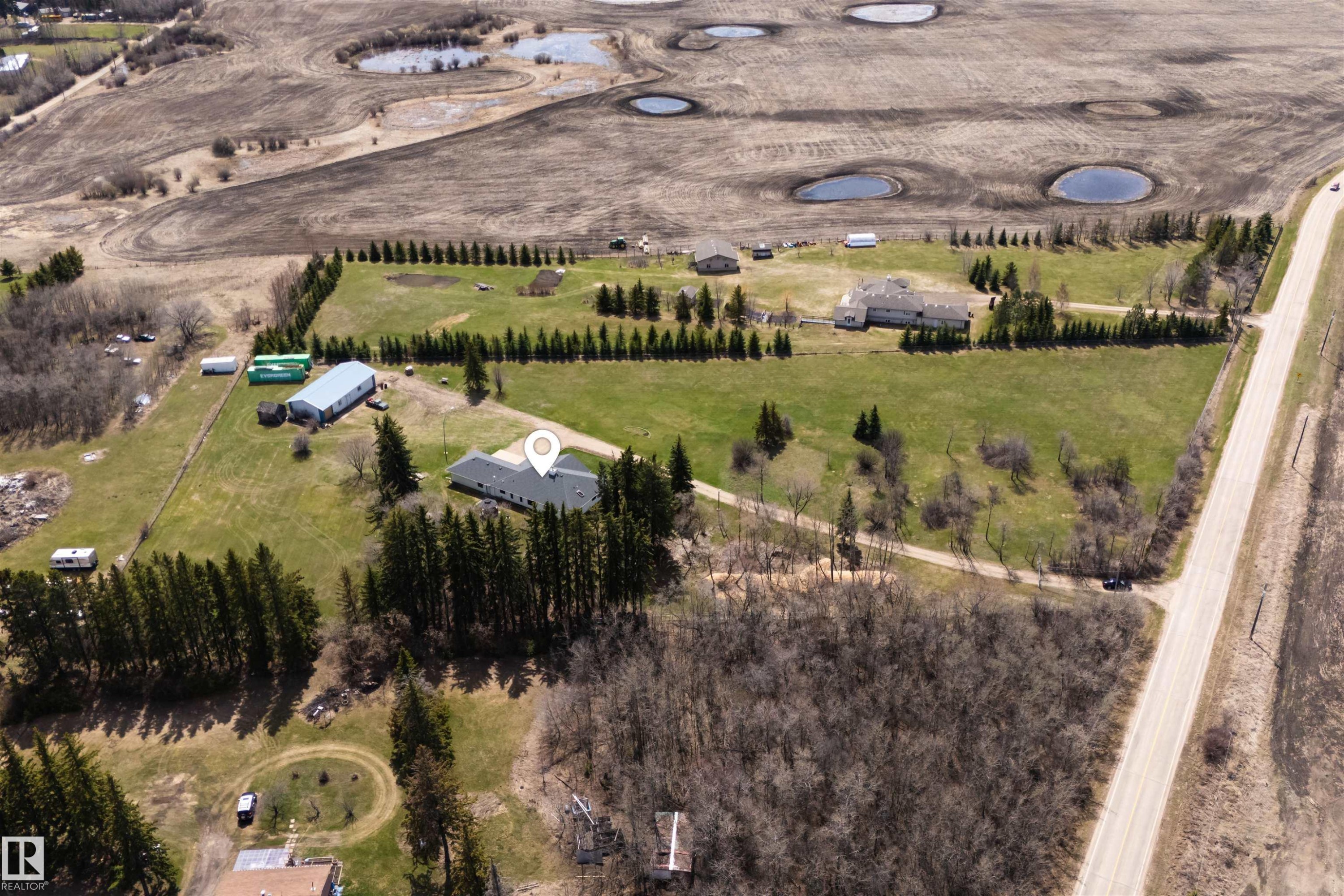 Expansive rural property featuring multiple structures including a main residence with a dark shingle roof, a large metal-clad outbuilding, and additional smaller structures - 19403 Fort Road, Edmonton, AB - Outdoor With View