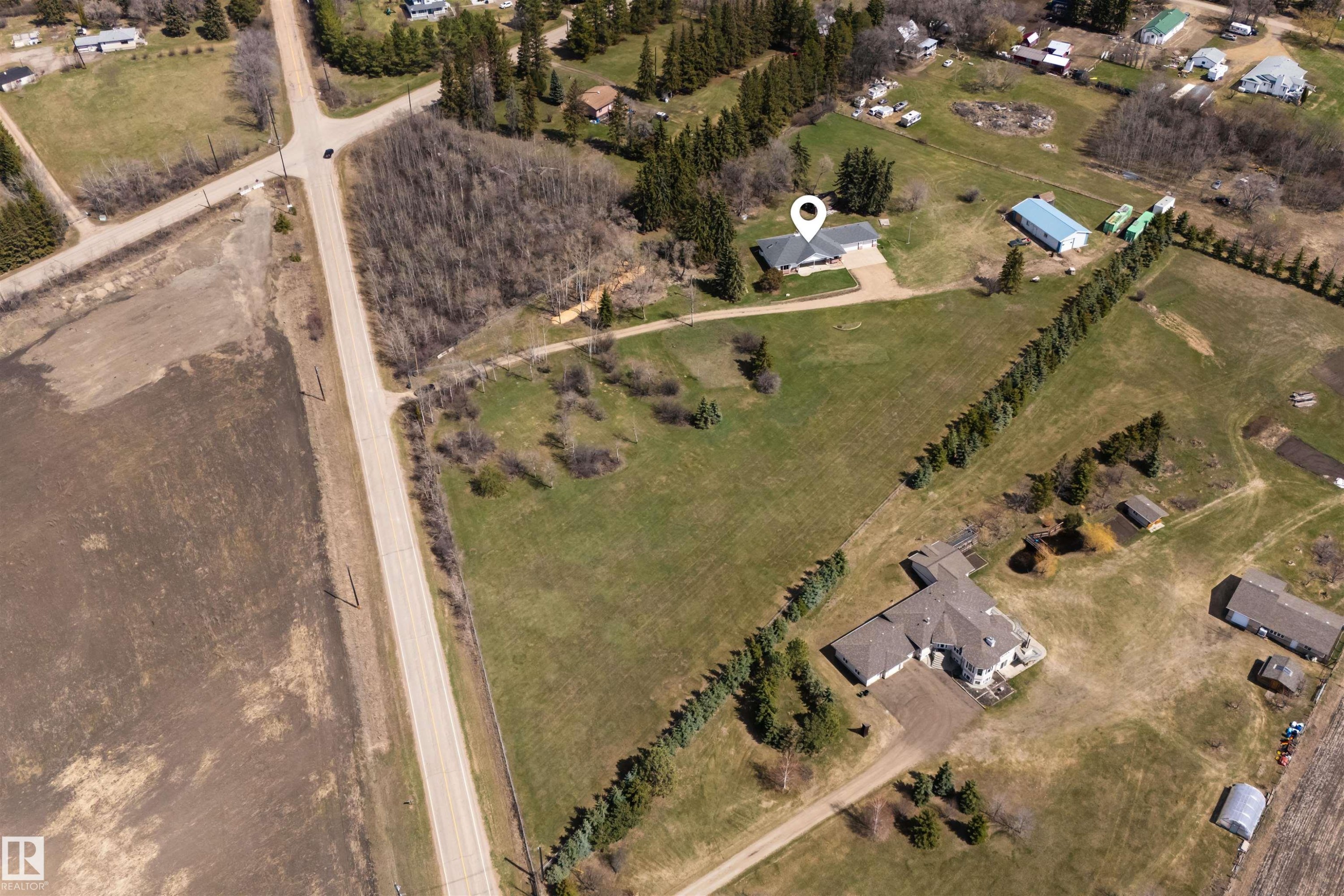 Spacious property featuring a single-story residence with an attached garage, a large detached workshop, extensive green space, and mature tree lines - 19403 Fort Road, Edmonton, AB - Outdoor With View