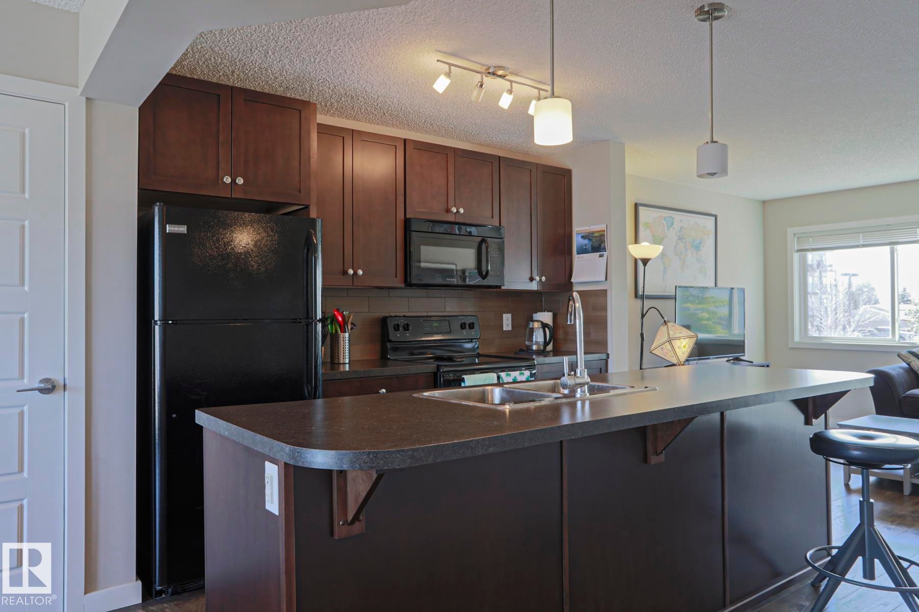 Kitchen island with counter eat up seating - 1622 33A Street Nw, Edmonton, AB - Indoor Photo Showing Kitchen With Double Sink