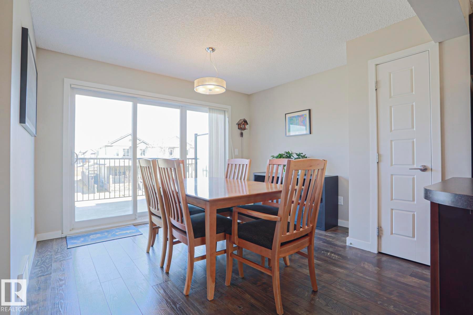 Dining area featuring laminate flooring, a contemporary pendant light fixture, and a sliding glass door leading to an oversized outdoor balcony - 1622 33A Street Nw, Edmonton, AB - Indoor Photo Showing Dining Room