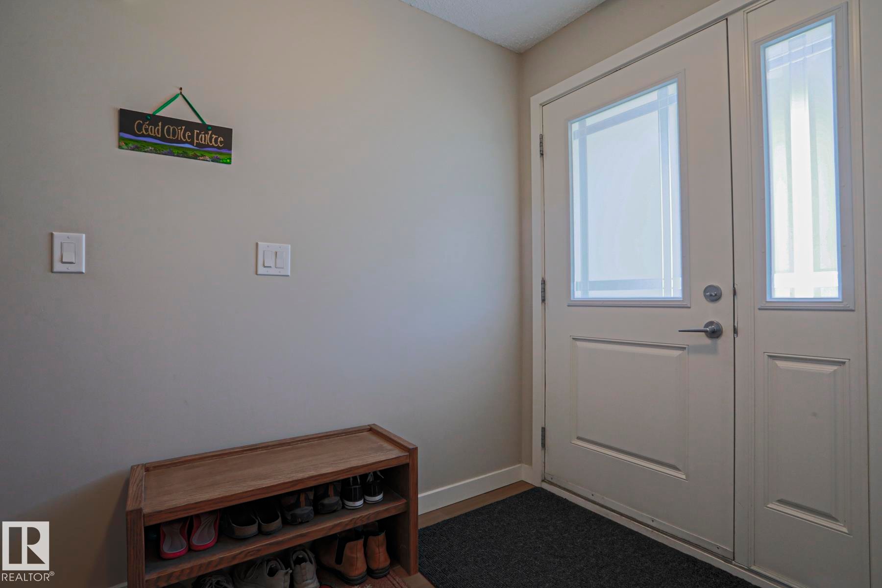 Entryway featuring a white paneled door with frosted glass insert, coordinating frosted glass sidelight, and light-toned wall paint - 1622 33A Street Nw, Edmonton, AB - Indoor Photo Showing Other Room