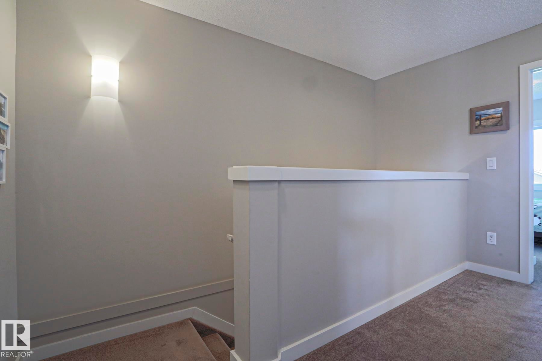 Upper third level living area. Carpeted staircase with white baseboards and a coordinating half-wall railing - 1622 33A Street Nw, Edmonton, AB - Indoor Photo Showing Other Room