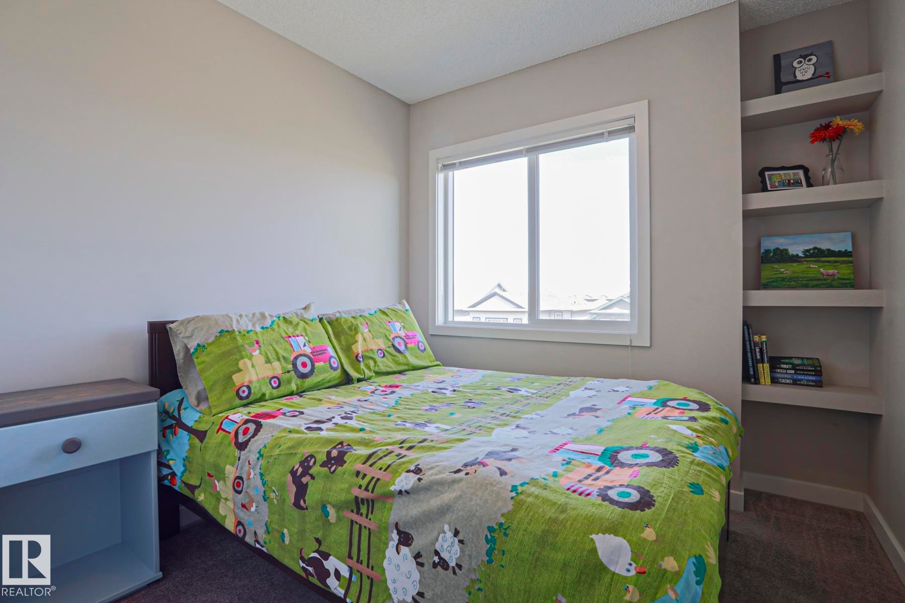 2nd Bedroom featuring a neutral wall color, built-in shelving, a single window, and carpet flooring - 1622 33A Street Nw, Edmonton, AB - Indoor Photo Showing Bedroom
